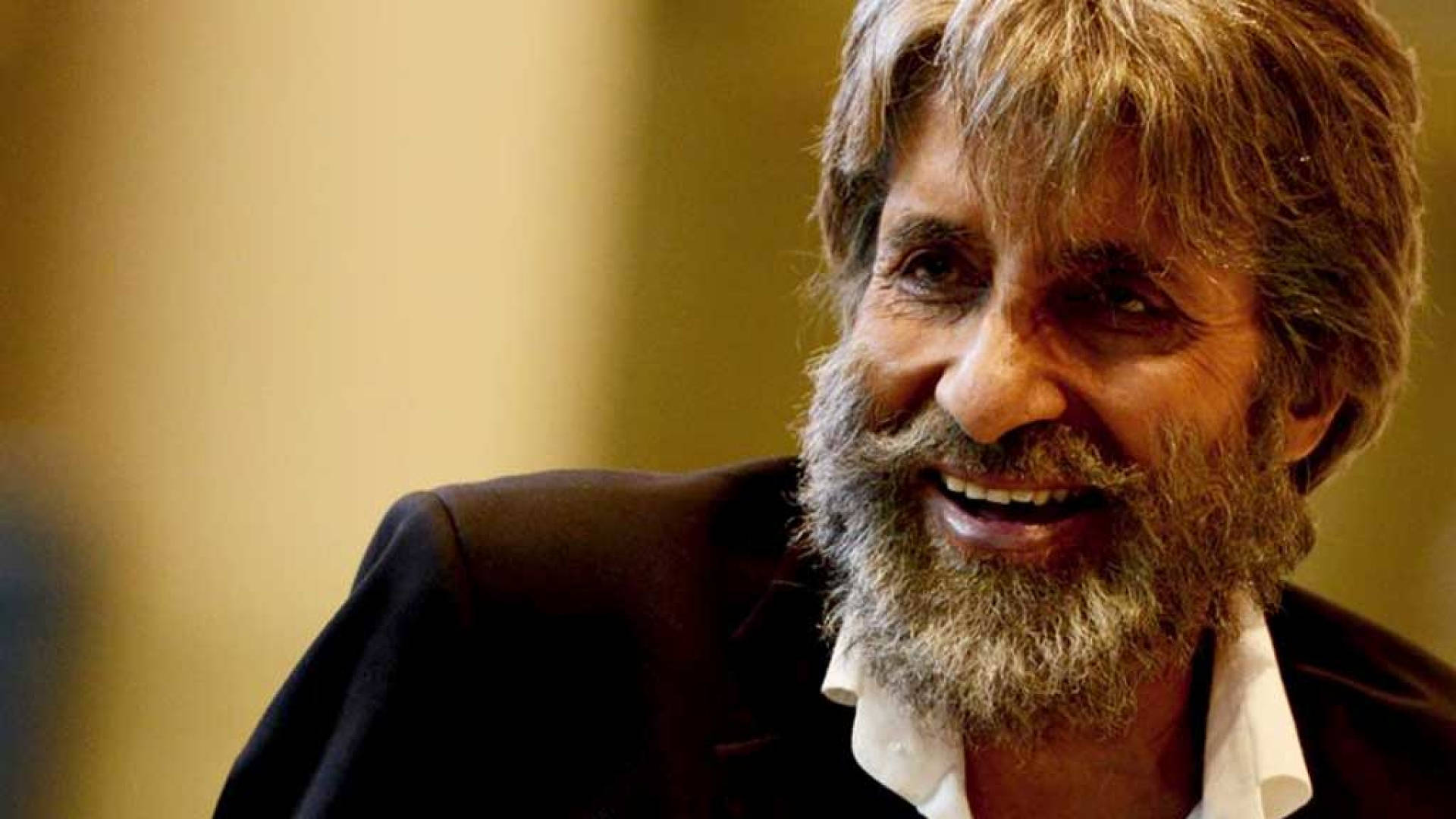 Amitabh Bachchan 桌布 壁紙 — 一位微笑男士的近照，灰白頭髮和鬍鬚，穿著深色西裝和白襯衫。