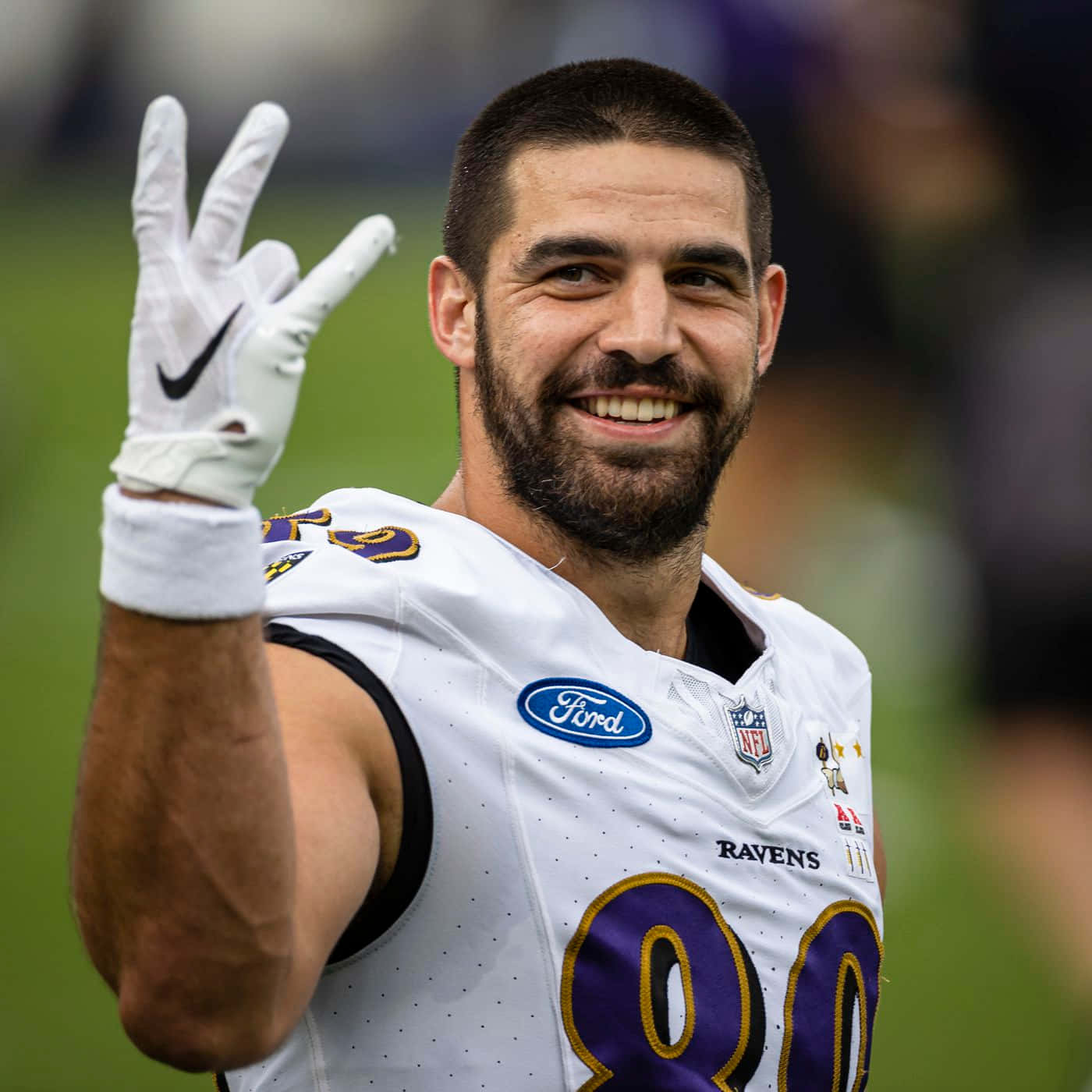 身穿烏鴉隊球衣的NFL球員微笑並伸出兩根手指揮手 — 巴爾的摩烏鴉隊 GIF 壁紙
