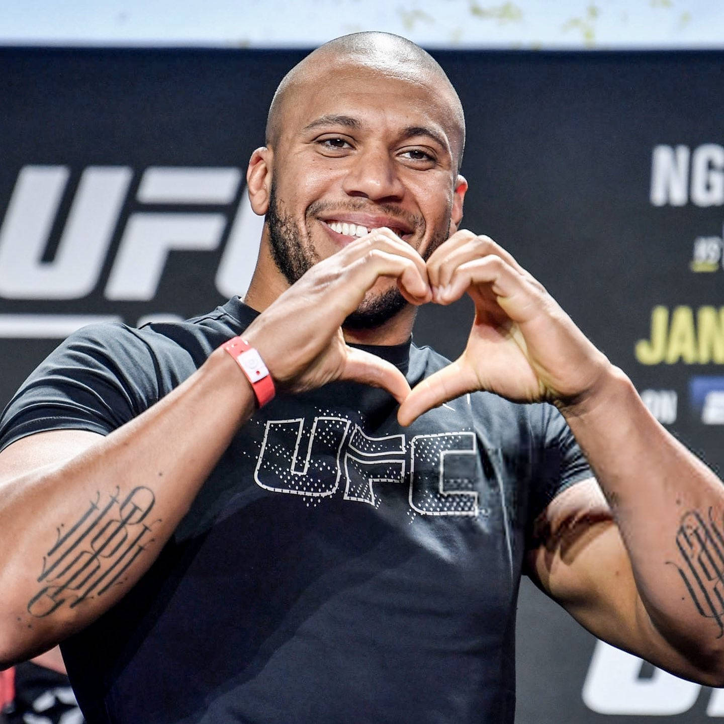 MMA 桌布 壁紙 — 一位微笑的UFC拳手在記者會上穿著品牌襯衫，用手做出心形。