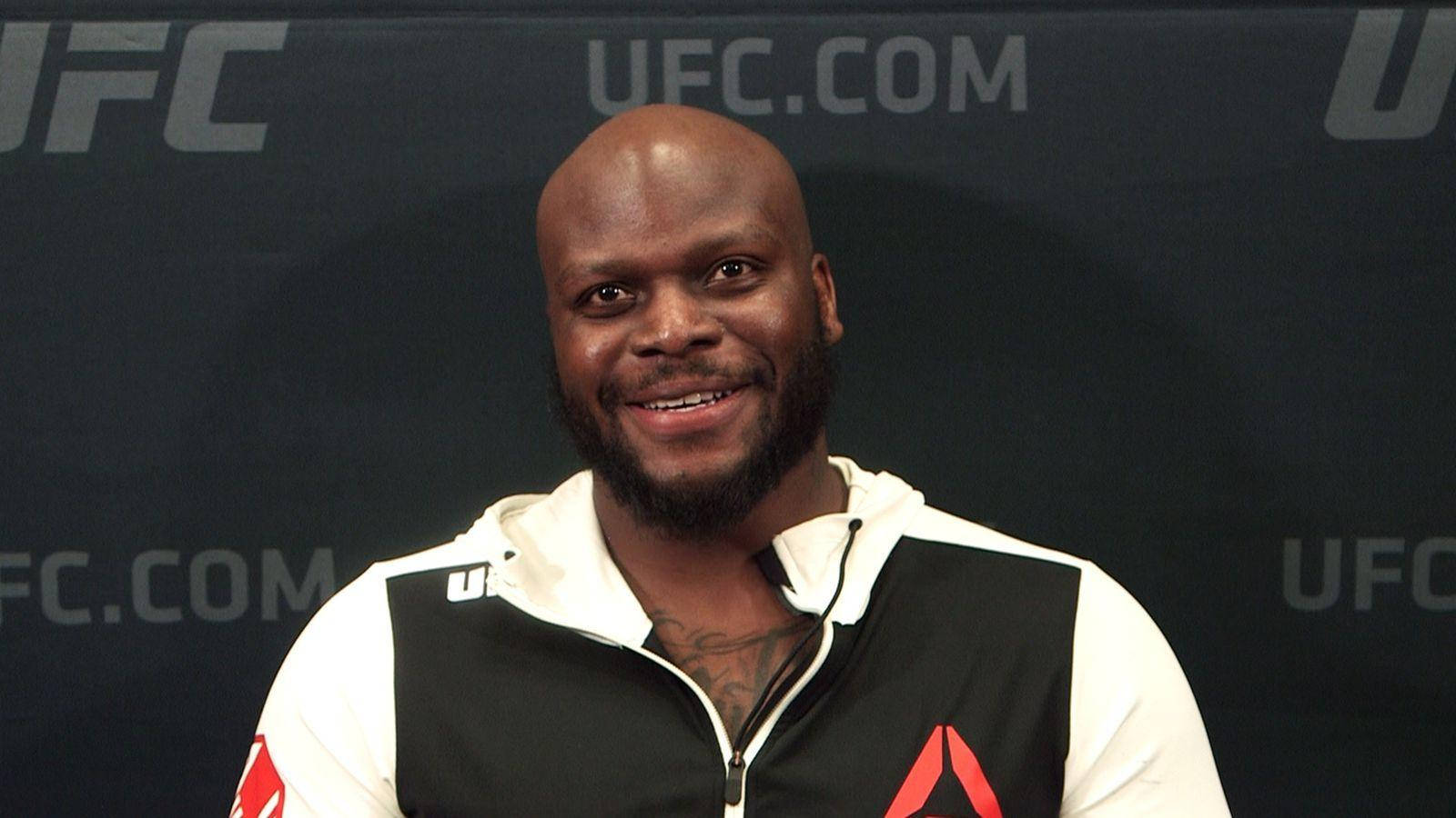 UFC 桌布 壁紙 — 一位微笑的光頭黑人男性留著鬍鬚，穿著黑白UFC品牌連帽衫，背景為深色並帶有UFC標誌。