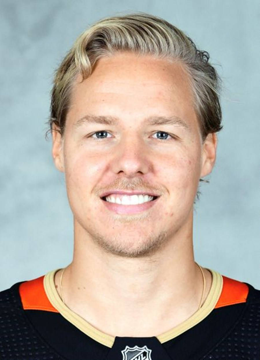 hockey 桌布 壁紙 — 一位微笑的冰球運動員，金髮藍眼，身穿黑色、橙色和金色的NHL球衣，背景為灰色攝影棚。