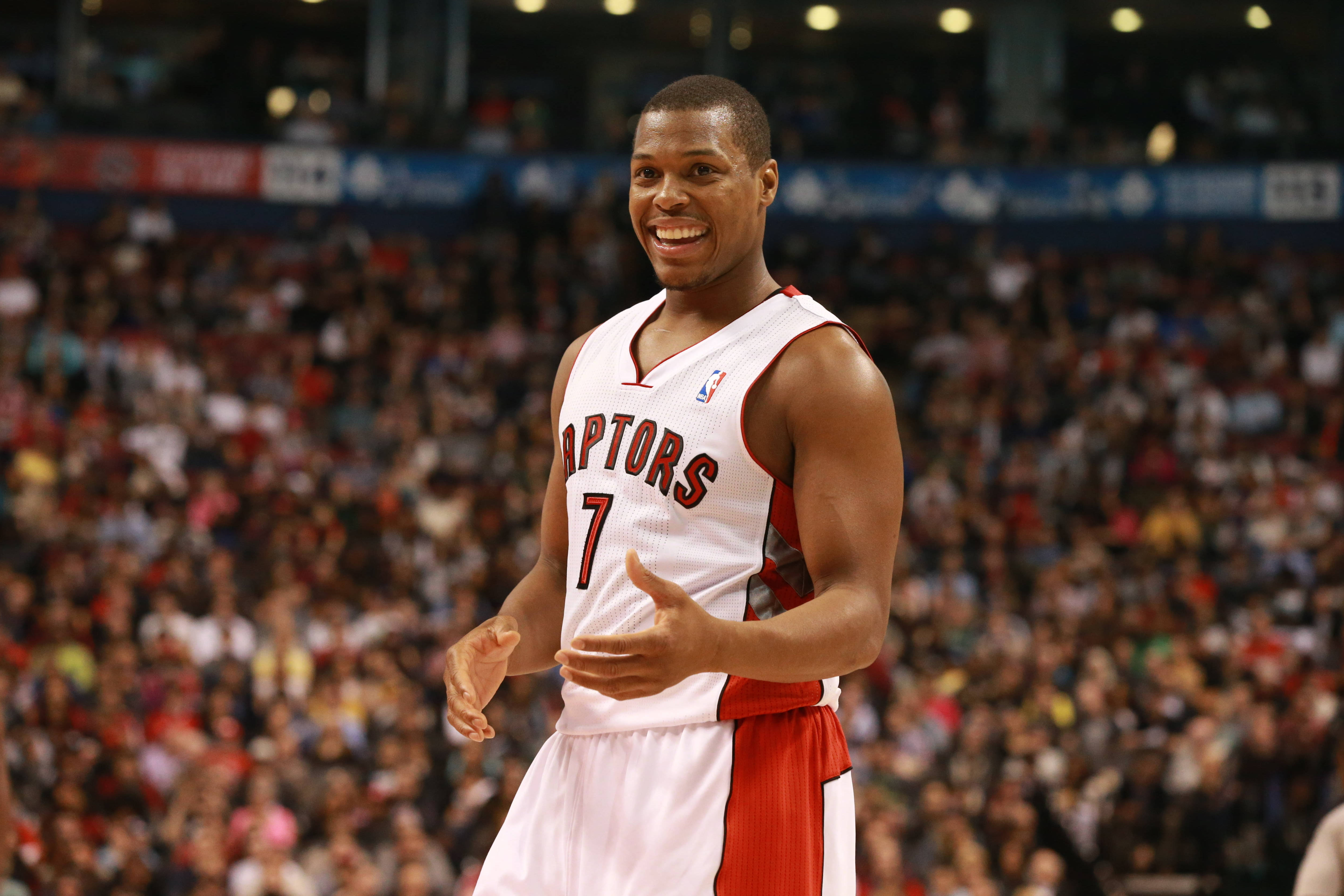 Lowry 桌布 壁紙 — 一位微笑的多倫多暴龍籃球運動員，身穿白色和紅色7號球衣，在比賽中向人群做手勢。