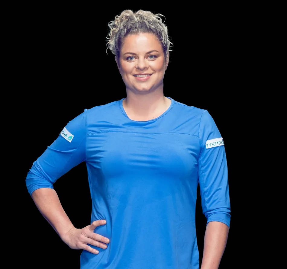 Kim Clijsters 桌布 壁紙 — 一位微笑的女士，灰色捲髮，穿著亮藍色運動衫，背景為黑色。