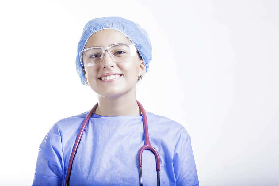 Nurse 桌布 壁紙 — 一位微笑的女外科醫生，身穿藍色手術服和帽子，脖子上掛著聽診器，自信地看著鏡頭。