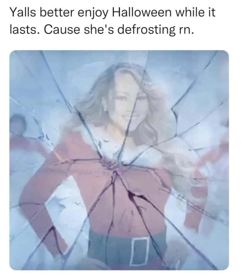 Holiday Memes 桌布 壁紙 — 一位微笑的女子穿著紅色精靈服裝，出現在破裂的玻璃後面，帶有冰藍色調和幽默的萬聖節迷因標題。