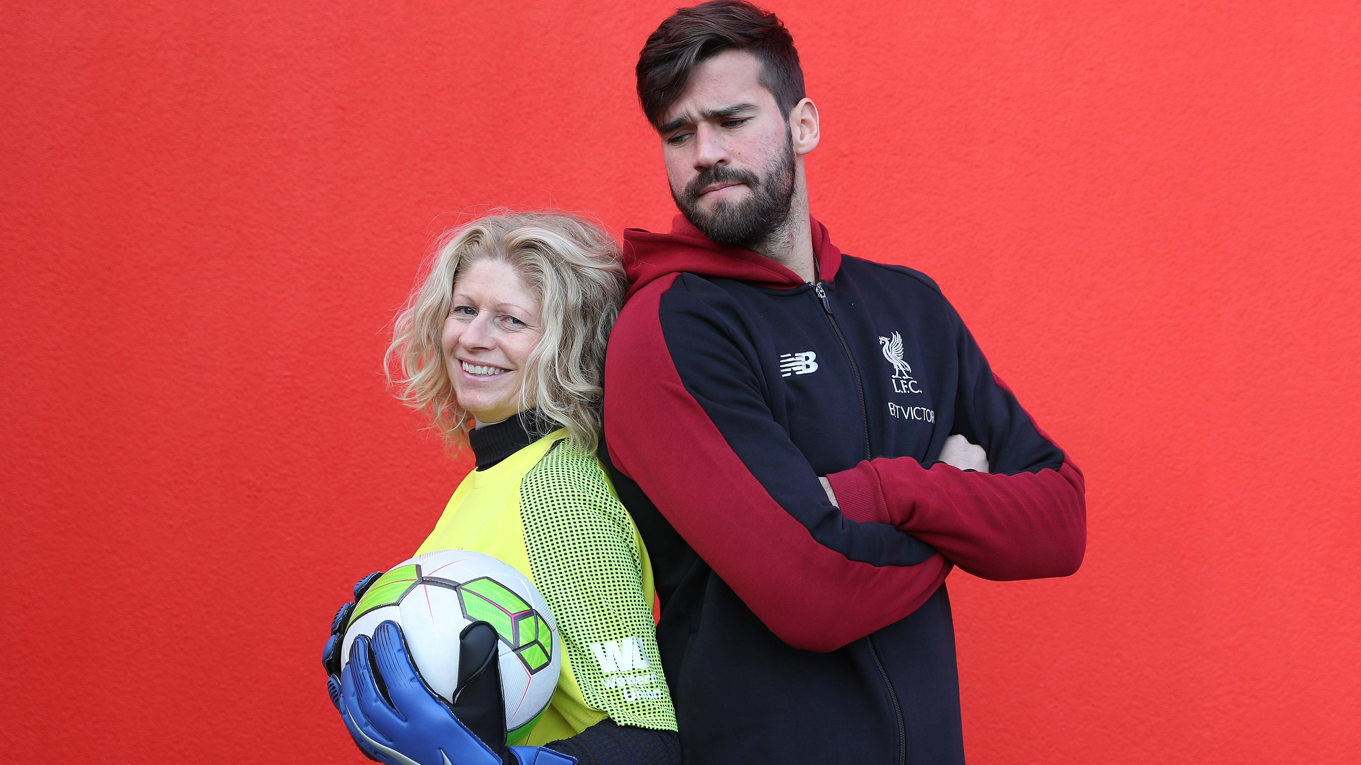 Alisson Becker 桌布 壁紙 — 一位微笑的女守門員身穿鮮黃色裝備，手持足球，站在一位身穿紅黑訓練服的嚴肅男球員旁邊，背景是一面鮮紅色的牆壁。