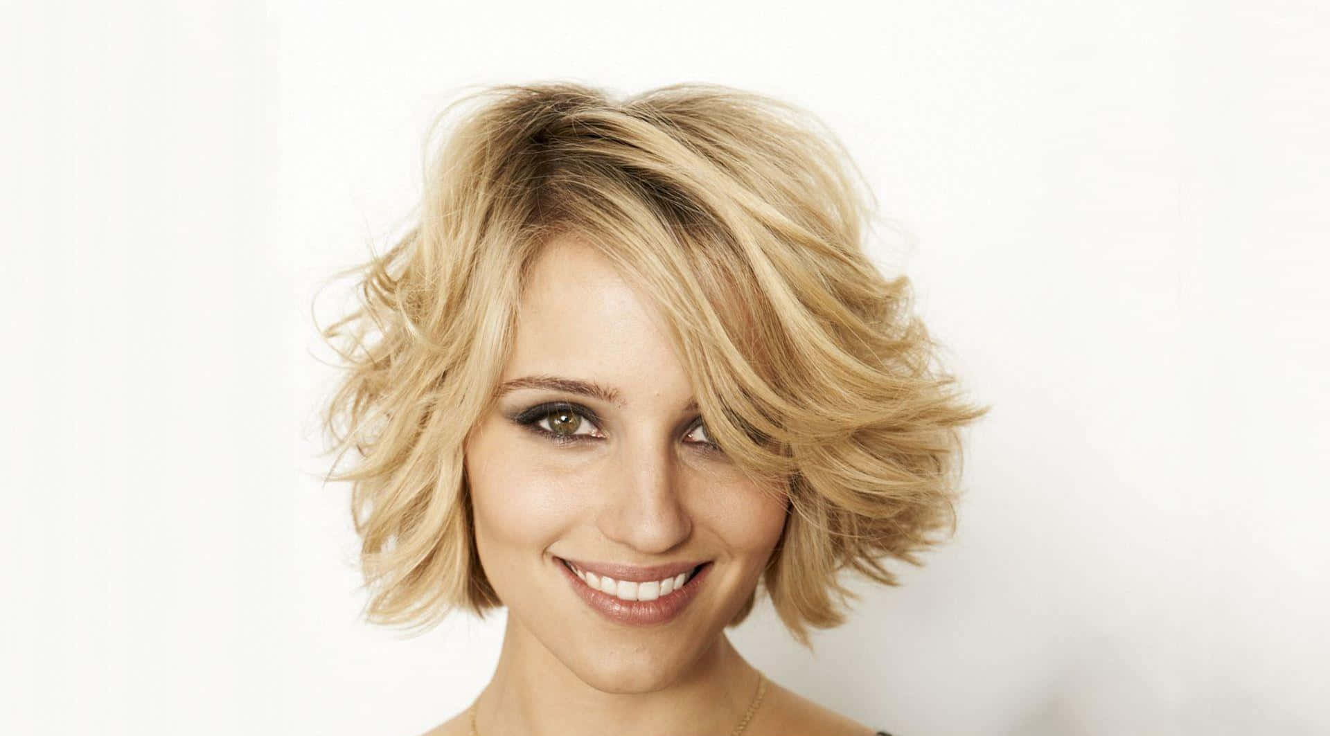dianna agron 桌布 壁紙 — 一位微笑的女性，擁有波浪金色鮑伯頭和綠色眼睛，背景為純白色。
