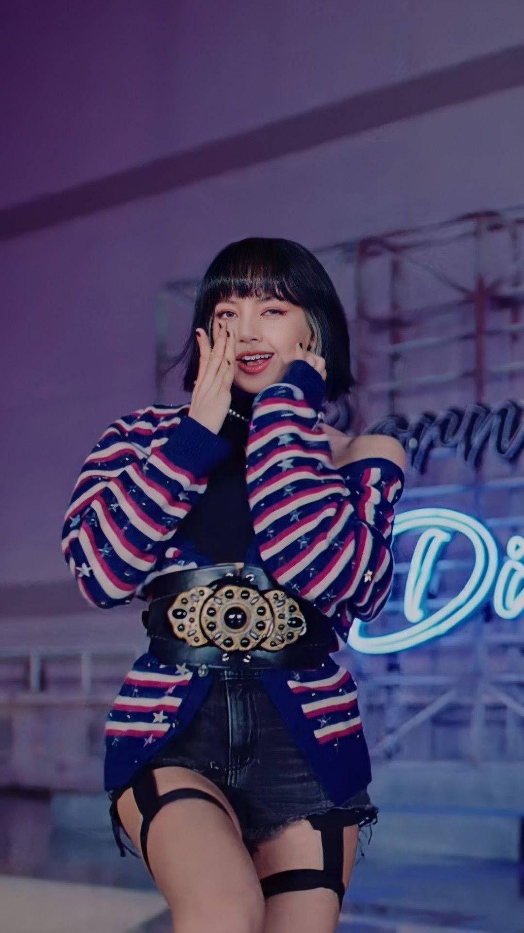 Lalisa 桌布 壁紙 — 一位微笑的女性穿著星星圖案毛衣和牛仔短褲，在紫色舞台燈光下將手靠近臉部擺姿勢。