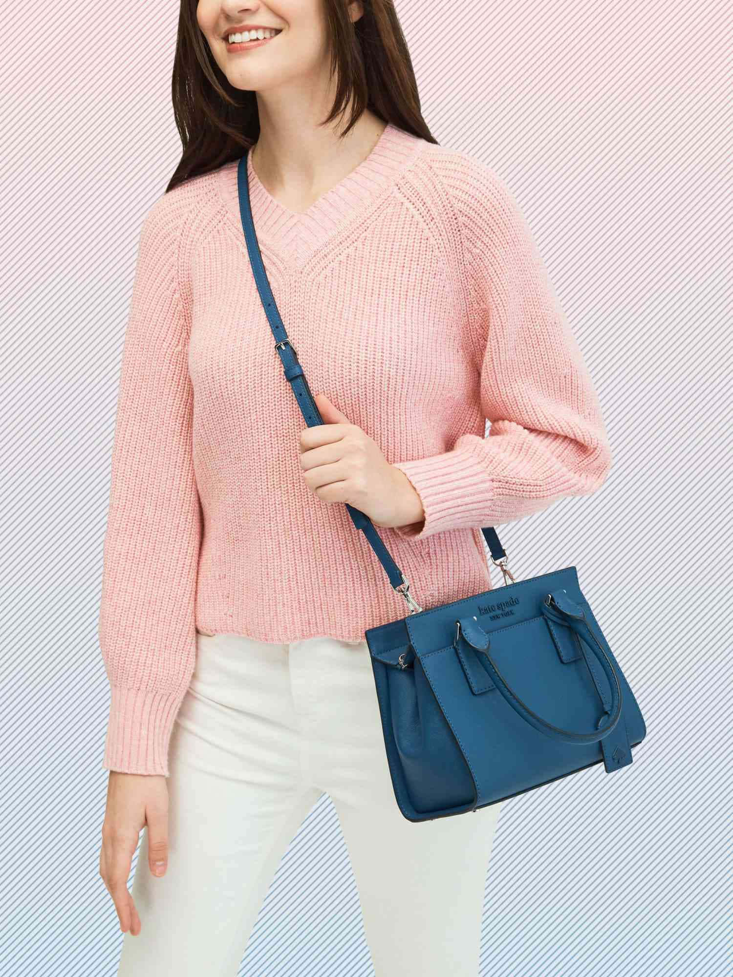 kate spade 桌布 壁紙 — 一位微笑的女性穿著粉紅色針織毛衣和白色褲子，在條紋背景前背著一個藍色斜背包。