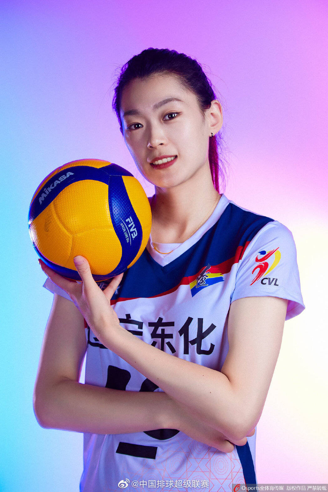桌布 壁紙 — 一位微笑的女排球運動員身穿白色和藍色制服，在充滿活力的紫色和藍色漸變工作室背景前拿著一個 Mikasa 排球。