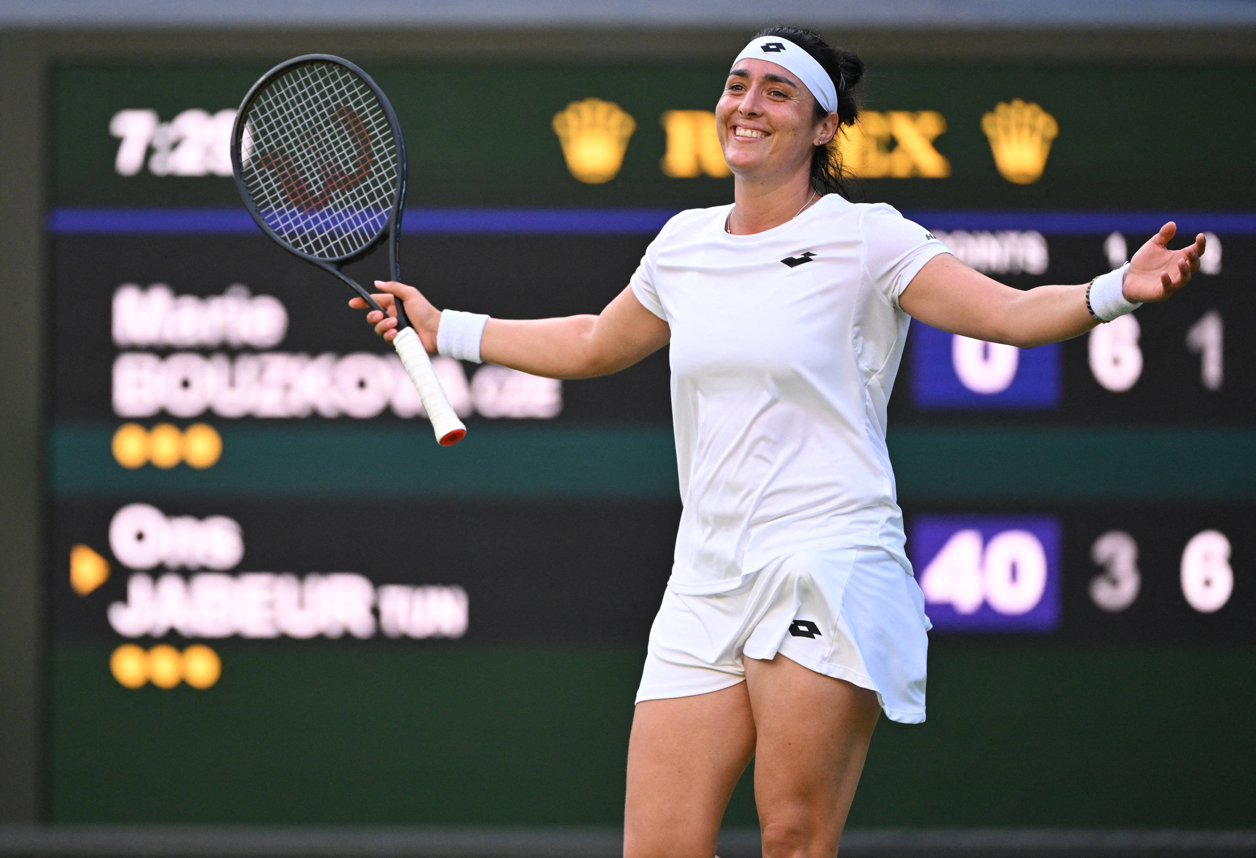 Athletic 桌布 壁紙 — 一位微笑的女網球選手在草地場上張開雙臂，手持球拍慶祝勝利。