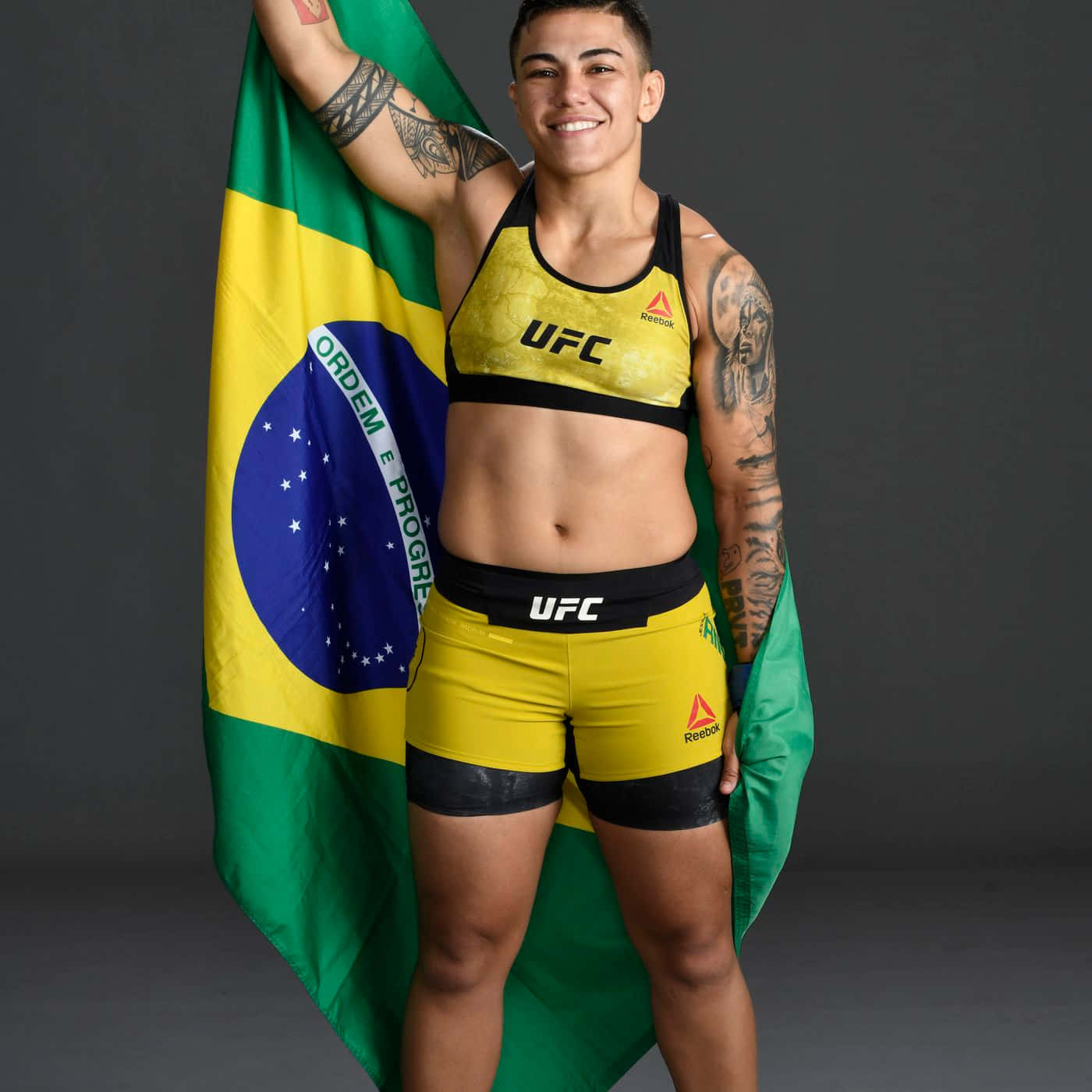 MMA 桌布 壁紙 — 一位微笑的巴西UFC拳手，自豪地披著國旗，在深色攝影棚背景下。
