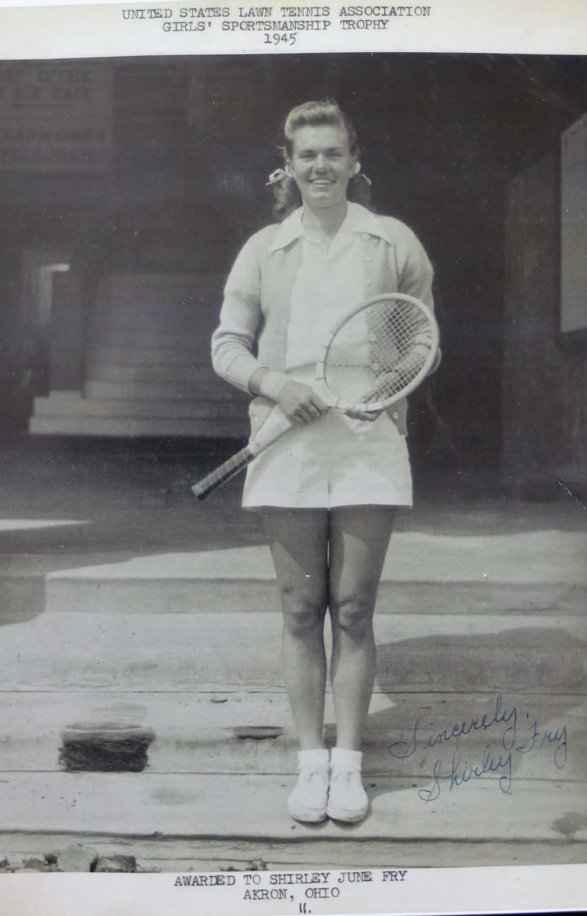 攝影 桌布 壁紙 — 一位微笑的年輕女子穿著復古網球服，在1940年代黑白照片中的石階上拿著球拍。