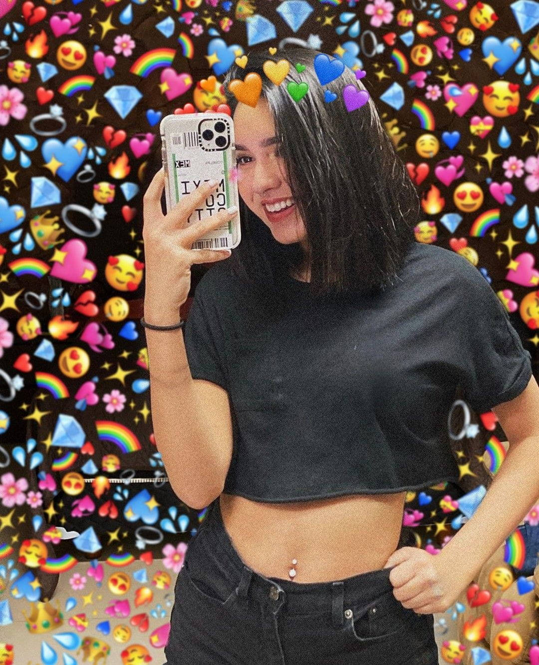 Tik Tok 桌布 壁紙 — 一位微笑的年輕女性在充滿活力的表情符號桌布前自拍，桌布上有愛心、彩虹和鑽石。