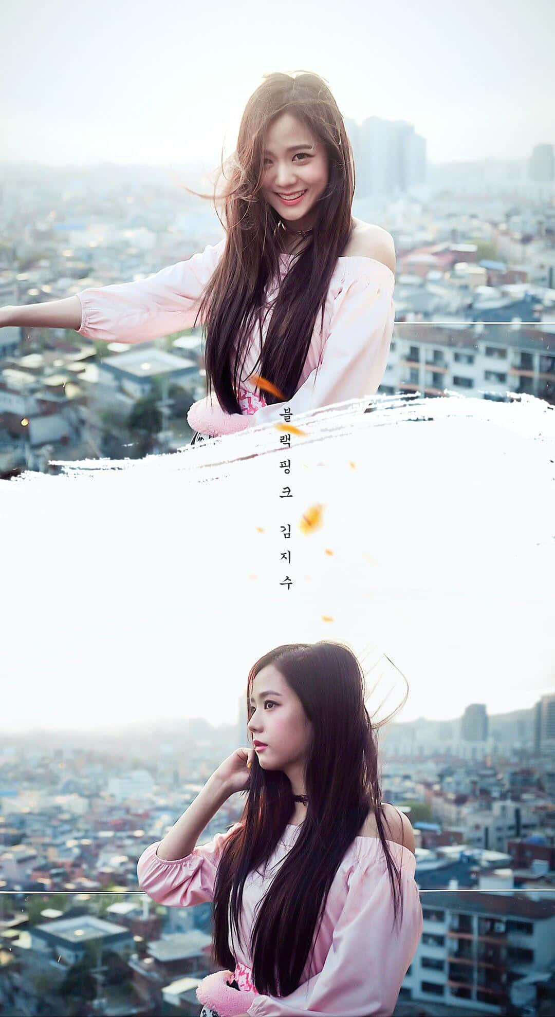 BLACKPINK 桌布 壁紙 — 一位微笑的年輕女性身穿粉紅色露肩上衣，在屋頂上擺姿勢，俯瞰著朦朧的城市景觀，風吹動她的頭髮。