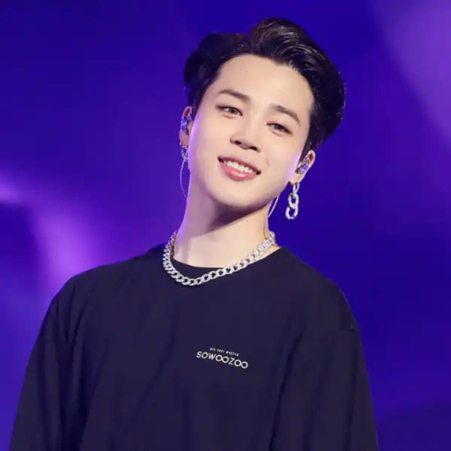BTS 智旻 桌布 壁紙 — 一位微笑的年輕男子，頭髮造型時尚，佩戴銀飾，身穿黑色T恤，背景是充滿活力的紫色舞台。