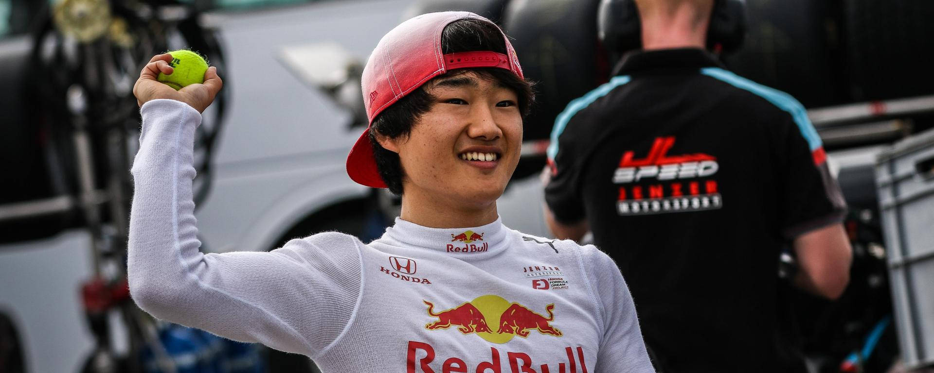 Racing 桌布 壁紙 — 一位微笑的年輕男子身穿Red Bull賽車服，在賽車活動中高舉一個亮綠色的網球。