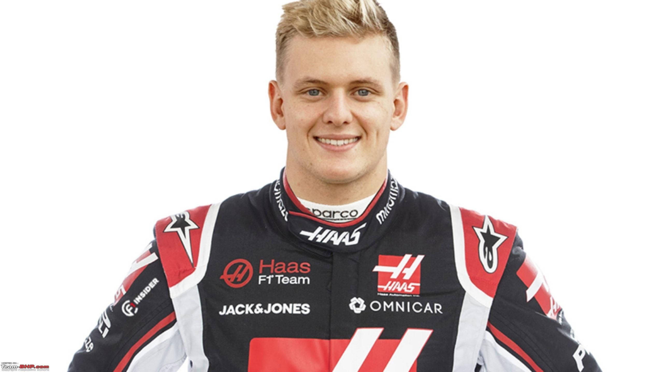 mick schumacher 桌布 壁紙 — 一位微笑的年輕賽車手，身穿黑、紅、白三色的Haas F1車隊賽車服，背景為純白色。
