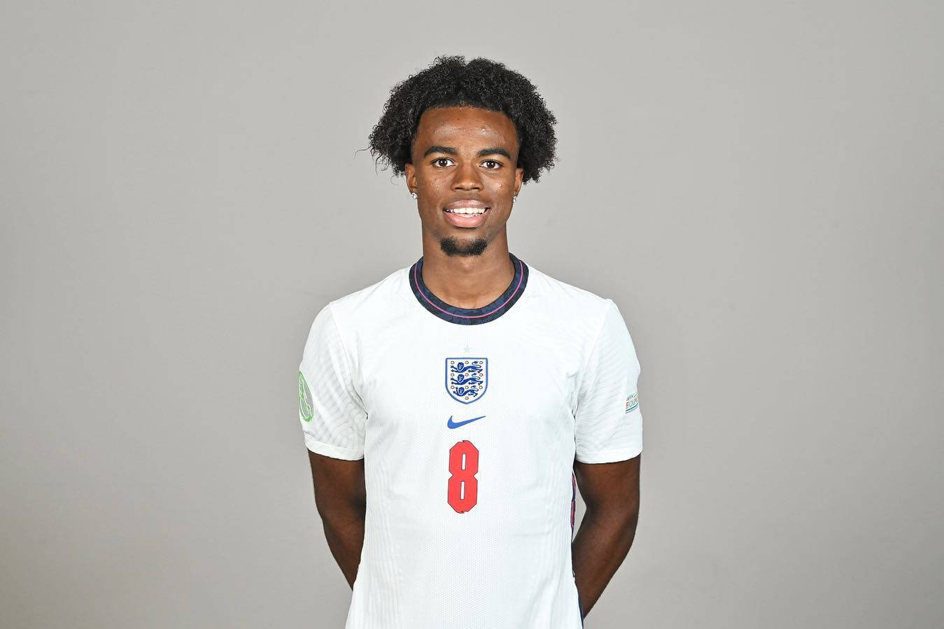 Football Players 桌布 壁紙 — 一位微笑的年輕足球員身穿英格蘭國家隊8號球衣，站在純灰色攝影棚背景前。