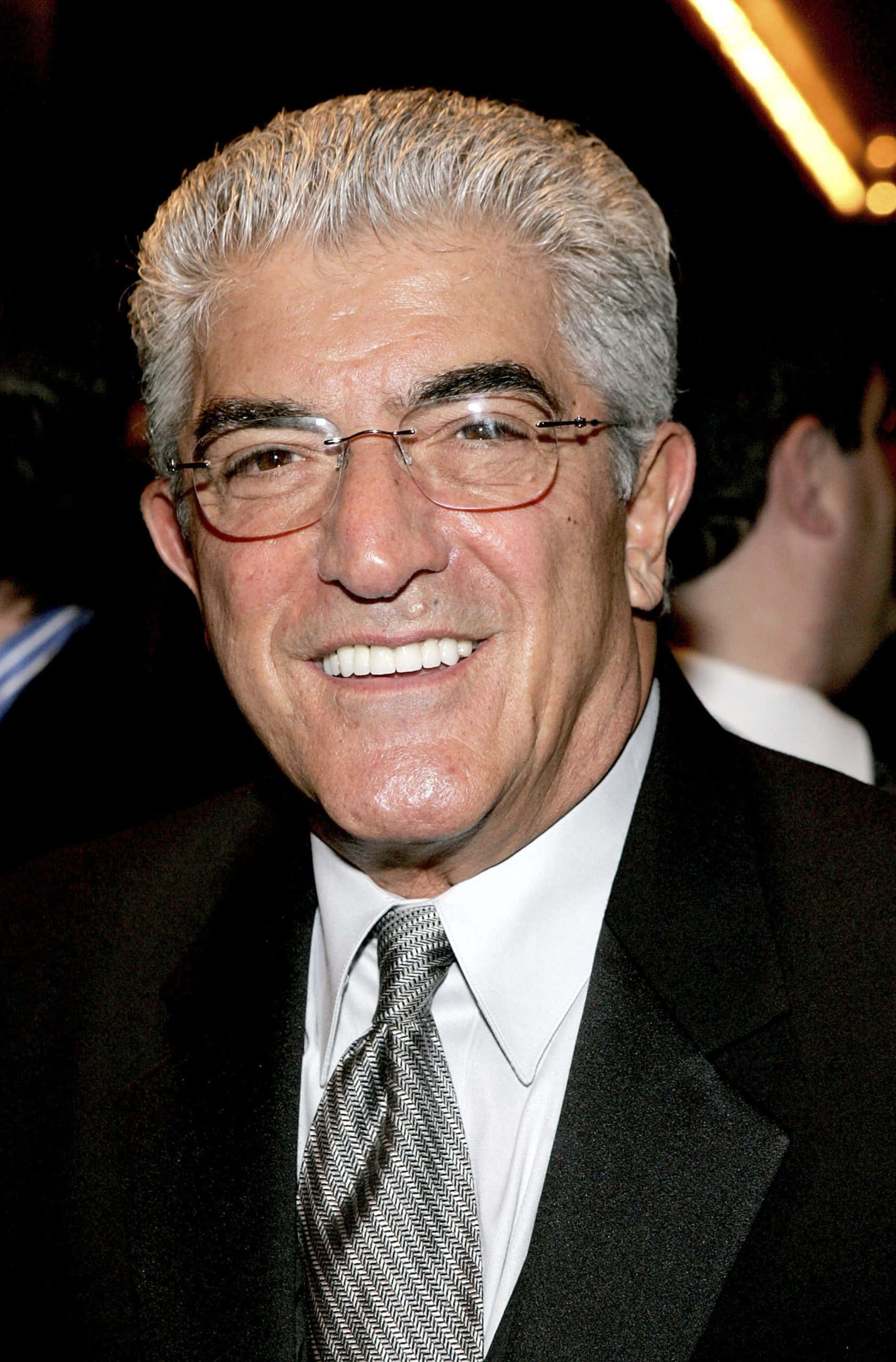 Frank Vincent 桌布 壁紙 — 一位微笑的年長男士特寫肖像，灰白頭髮，戴眼鏡，身穿黑色西裝和圖案領帶。