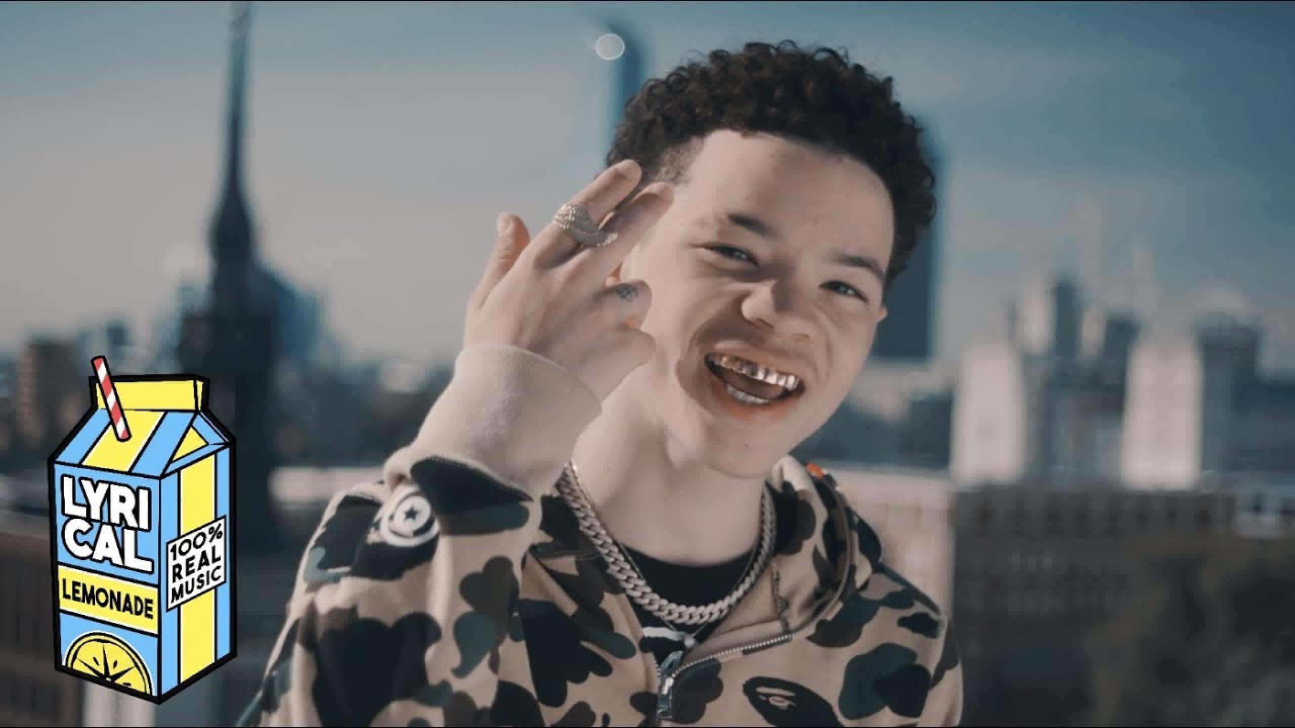 Lil Mosey 桌布 壁紙 — 一位微笑的捲髮年輕男子在模糊的城市天際線背景下愉快地揮手。