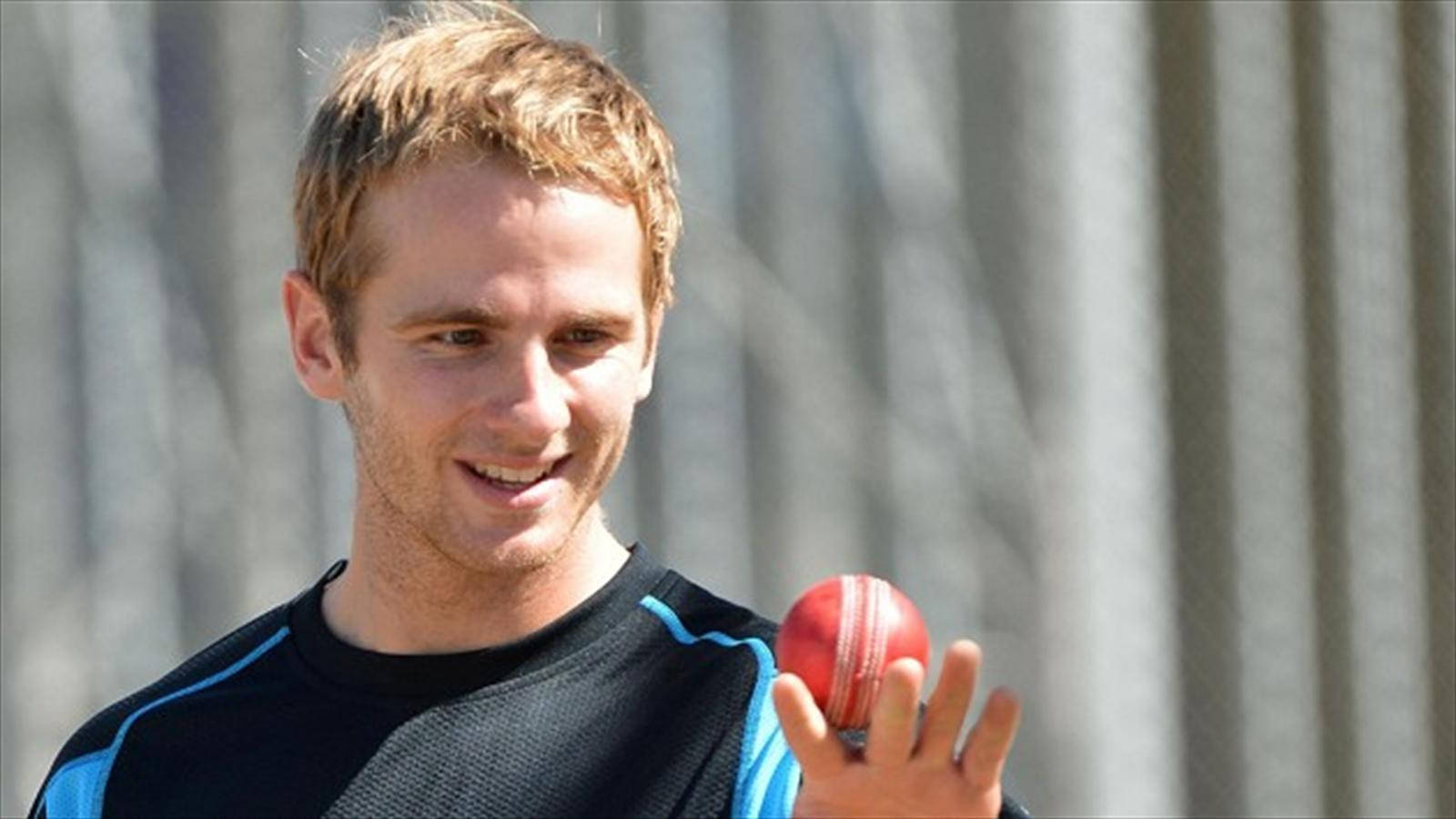 kane williamson 桌布 壁紙 — 一位微笑的板球選手在模糊的灰色波紋背景前手持一個紅色皮革板球。