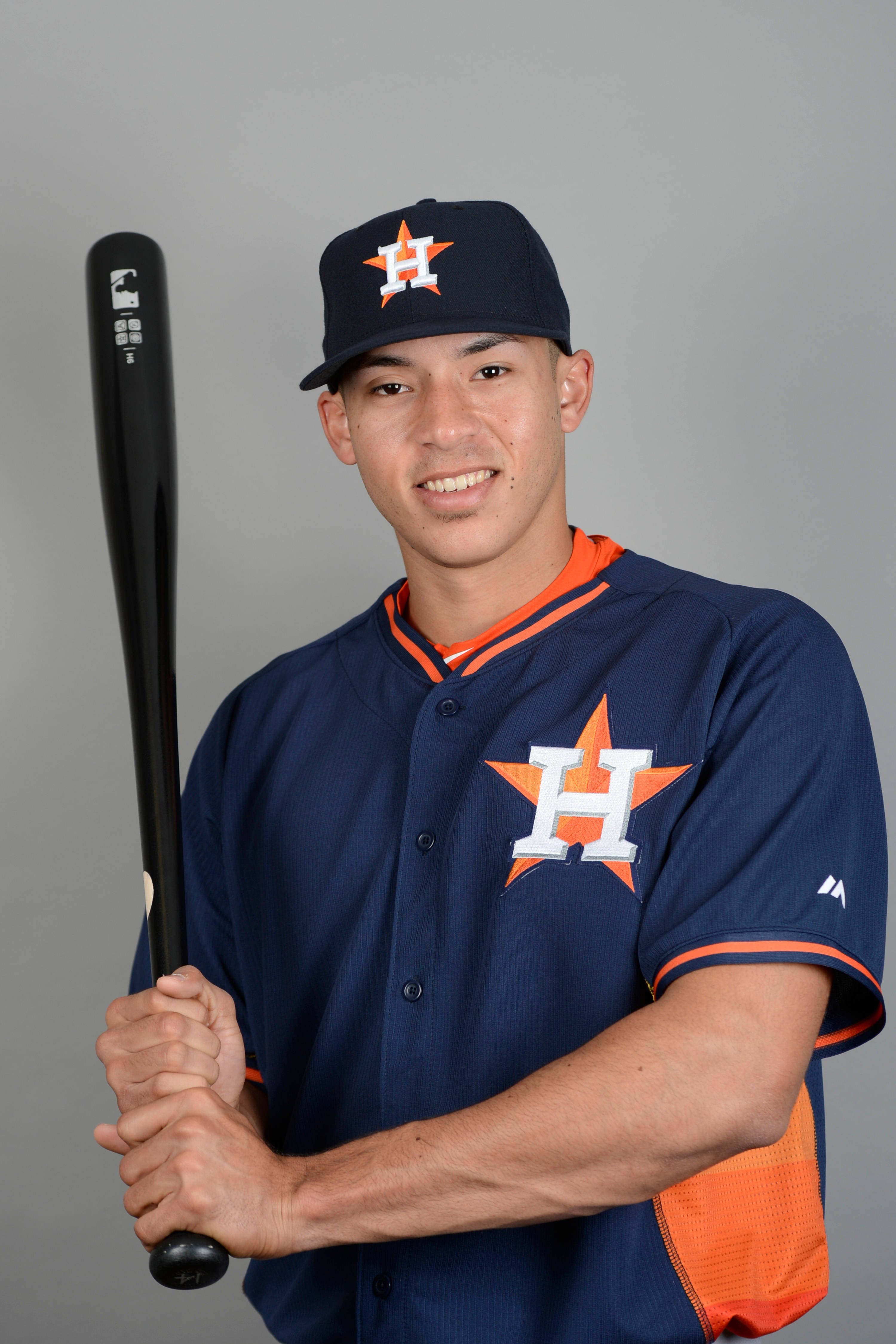 Carlos Correa 桌布 壁紙 — 一位微笑的棒球運動員身穿休士頓太空人隊制服，在純灰色攝影棚背景前握著一支黑色球棒。