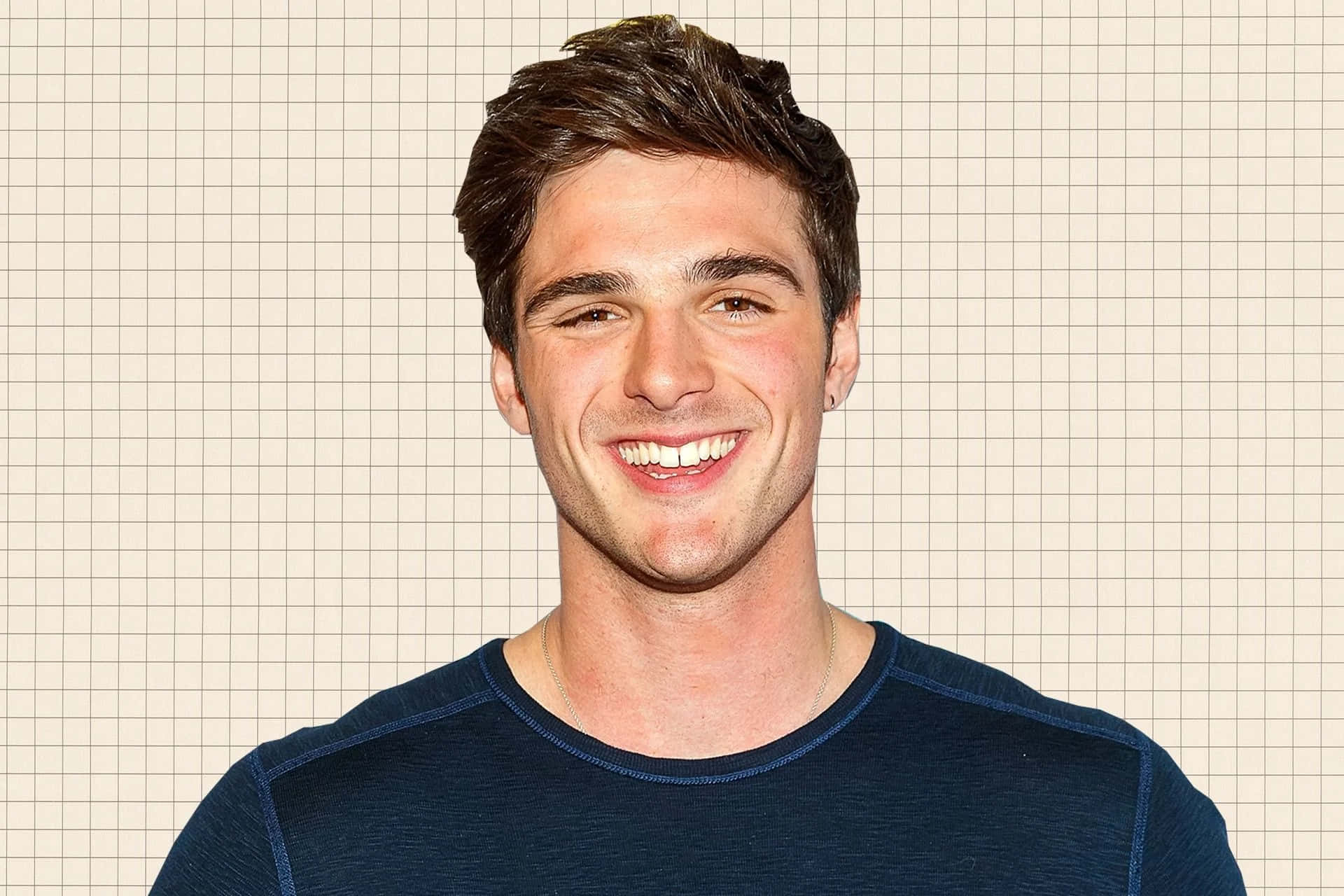 jacob elordi 桌布 壁紙 — 一位微笑的深色頭髮年輕男子穿著藍色襯衫，站在淺米色網格背景前。