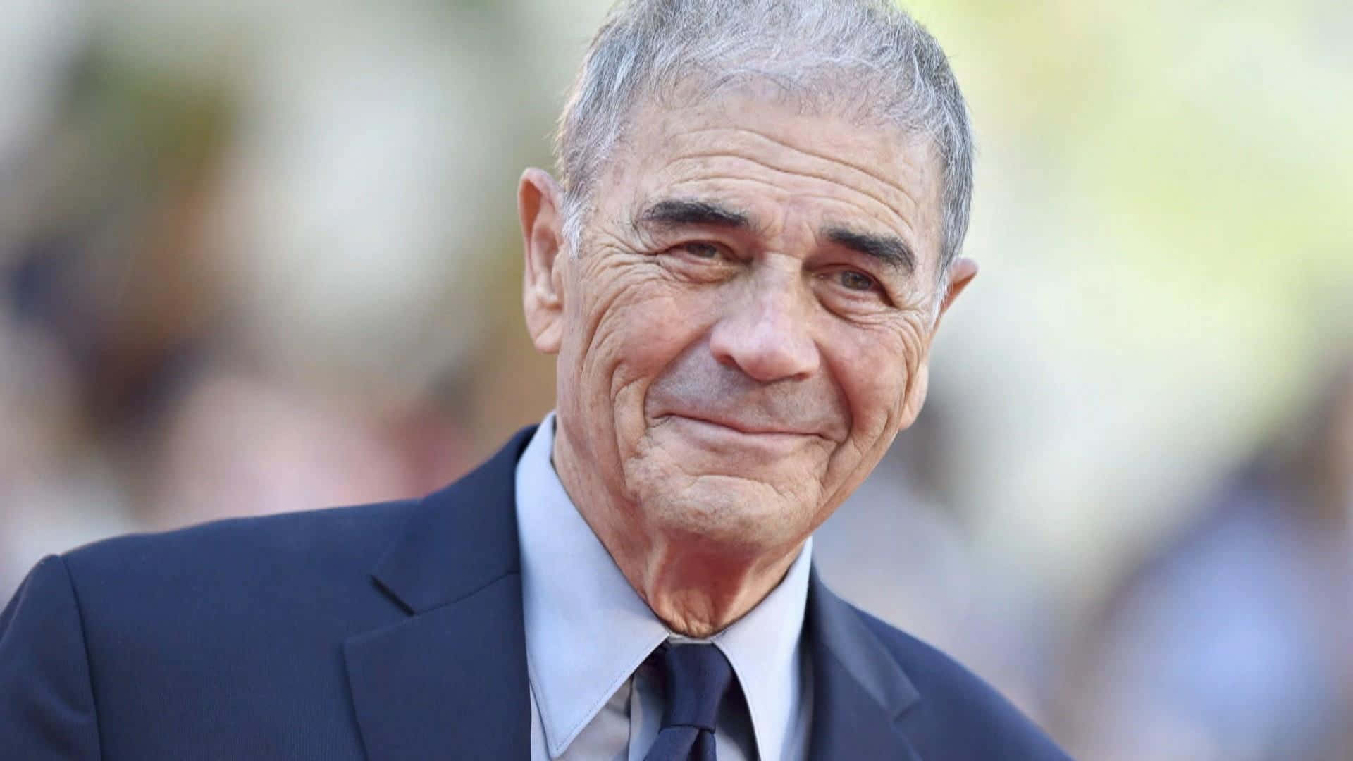 actor 桌布 壁紙 — 一位微笑的灰髮老年男子穿著深色西裝和領帶，背景模糊的特寫肖像。