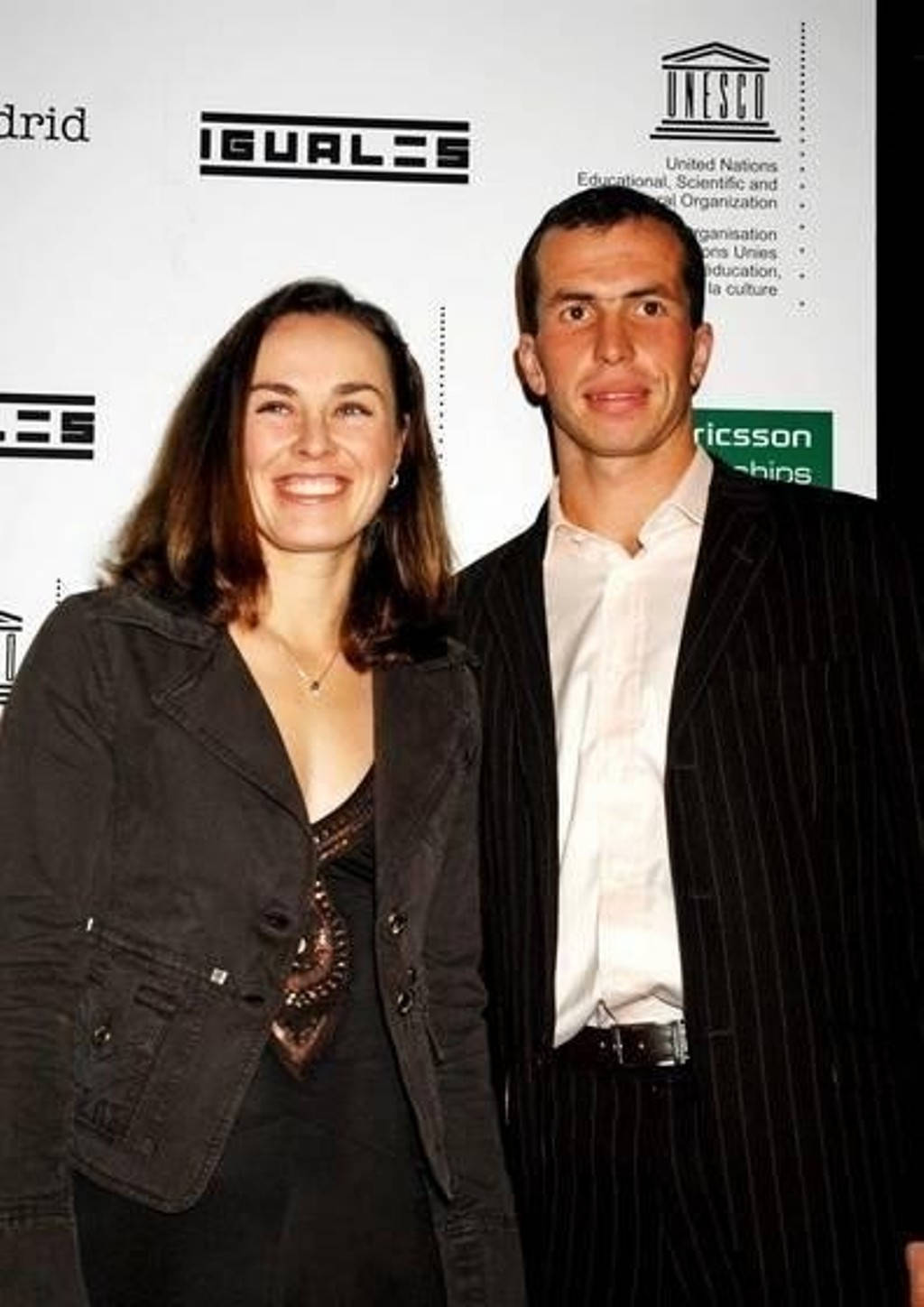 martina hingis 桌布 壁紙 — 一位微笑的男士和女士在一個正式活動中一起擺姿勢，背景有UNESCO和IGUALS標誌。