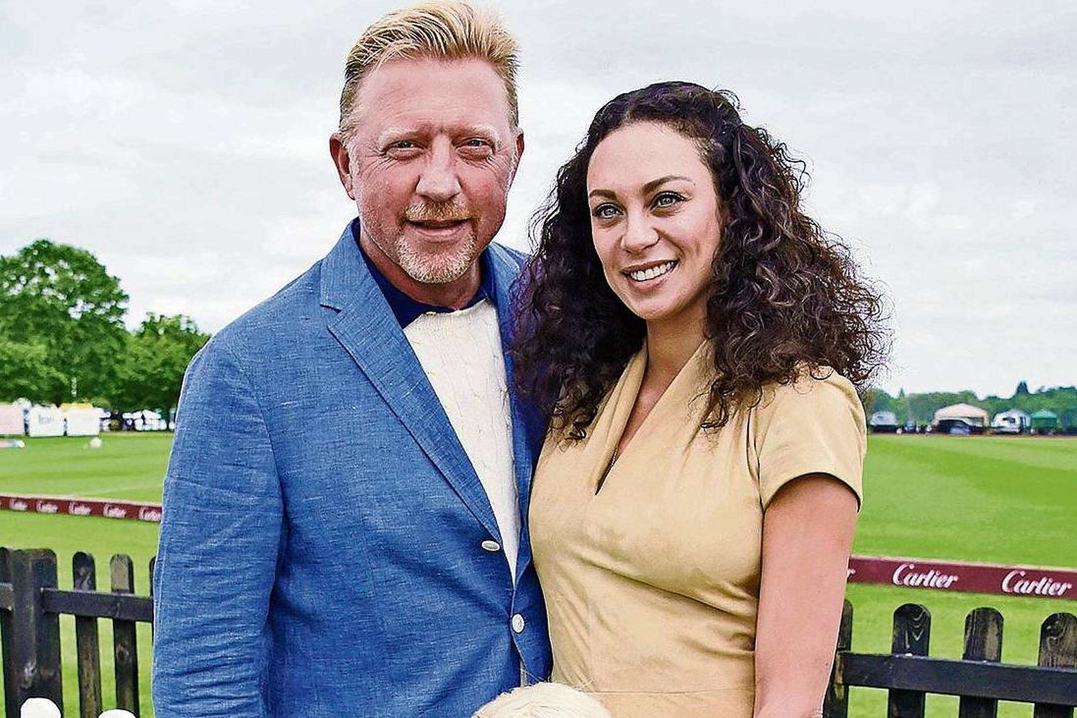 Boris Becker 桌布 壁紙 — 一位微笑的男士和女士在戶外馬術活動中一起擺姿勢，身後是綠色田野和帶有品牌的圍欄。