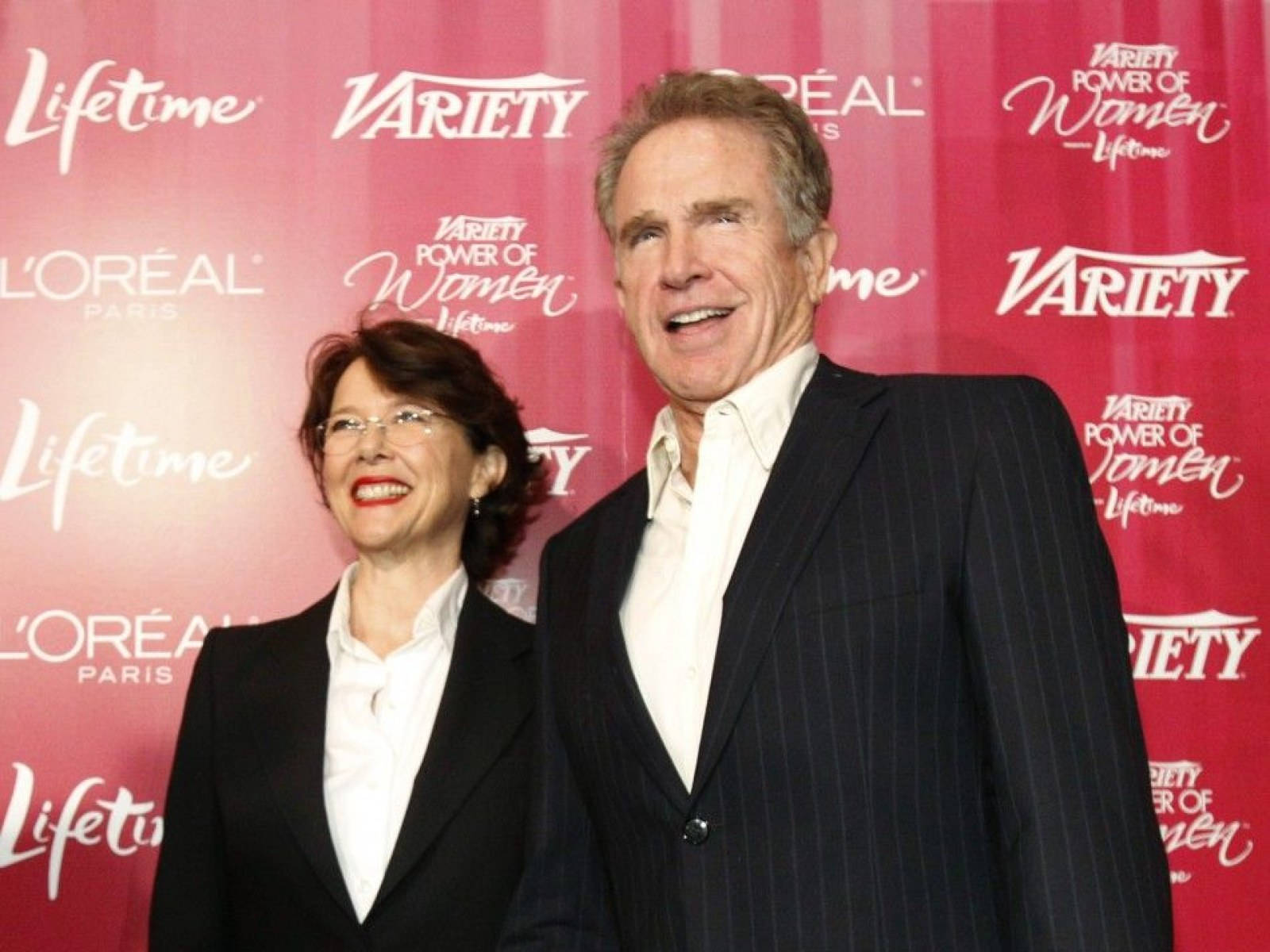 Celebrity 桌布 壁紙 — 一位微笑的男士和女士在有品牌背景的紅地毯活動中一起擺姿勢。