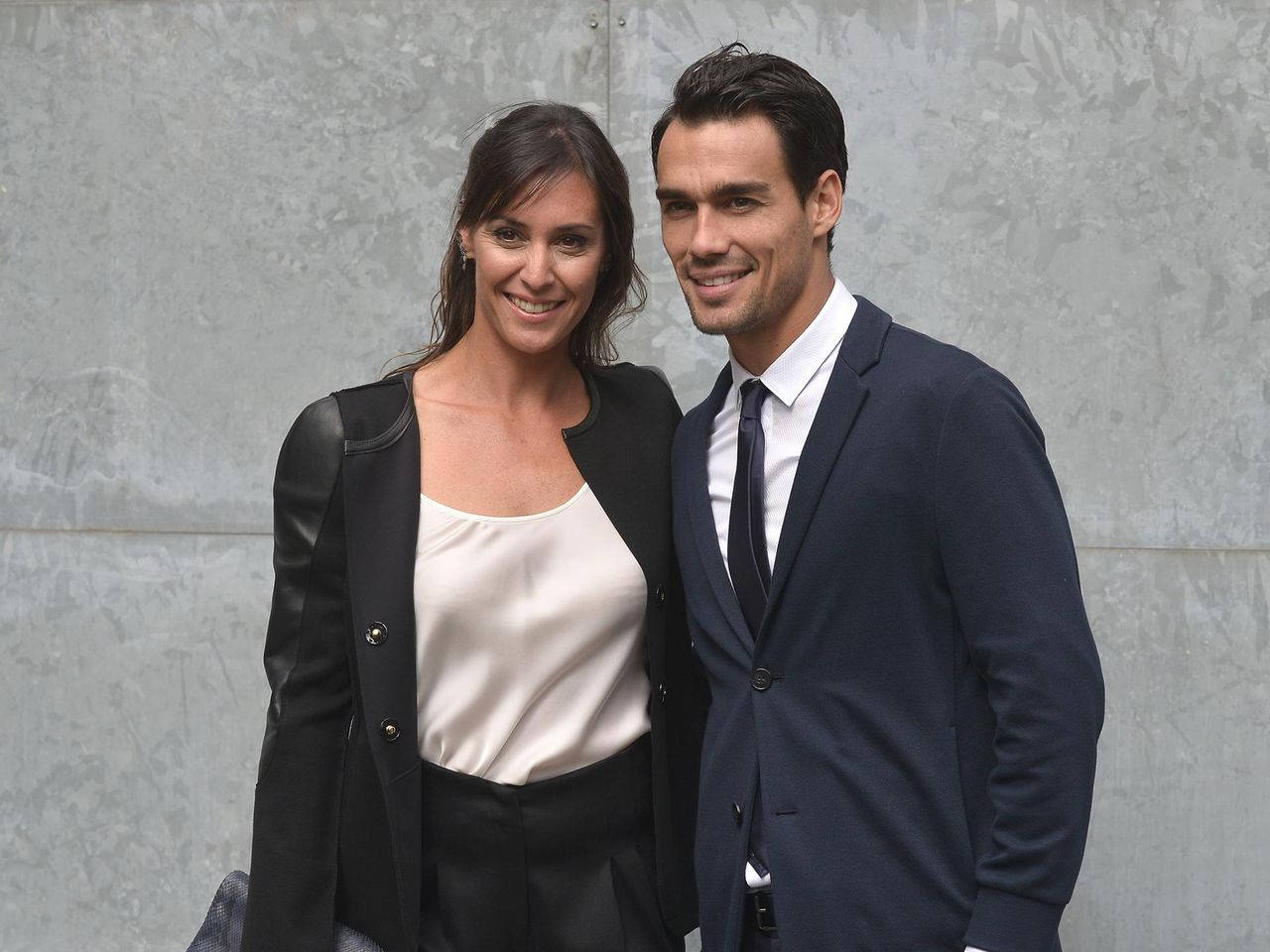 Tennis 桌布 壁紙 — 一位微笑的男士和女士穿著正式服裝，在灰色石牆前一起擺姿勢。