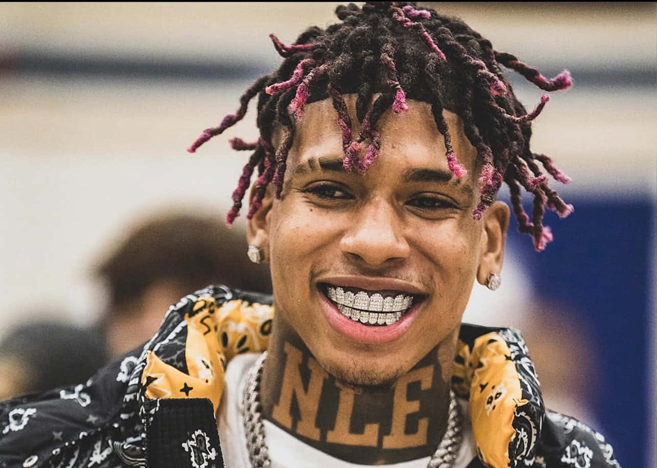 留著粉紅辮子和鑽石牙套的男子，頭戴頭巾，頸部有'NLE'刺青。 — NLE Choppa GIF 壁紙