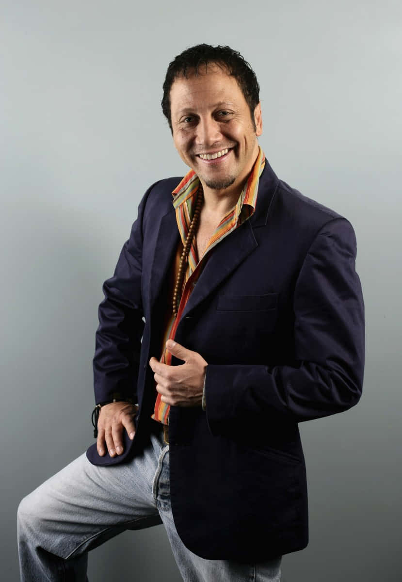 actor 桌布 壁紙 — 一位微笑的男子穿著海軍藍西裝外套和條紋襯衫，在純灰色攝影棚背景前自信地擺姿勢。