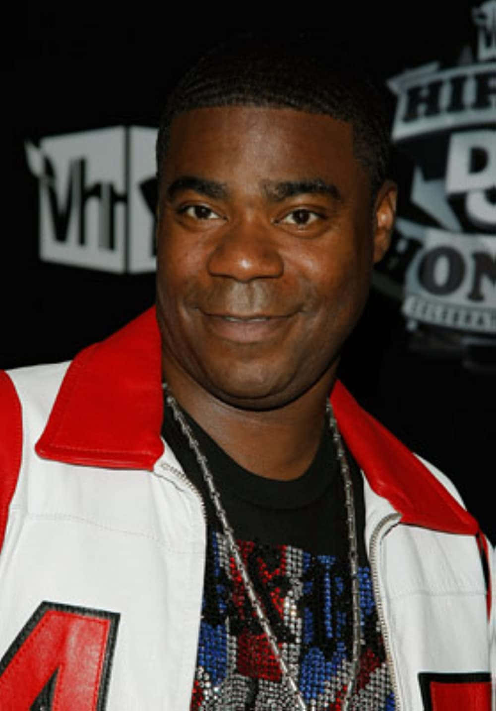 Tracy Morgan 桌布 壁紙 — 一位微笑的男子穿著白色外套、紅色領口和鑲有寶石的襯衫，在VH1活動中擺姿勢。