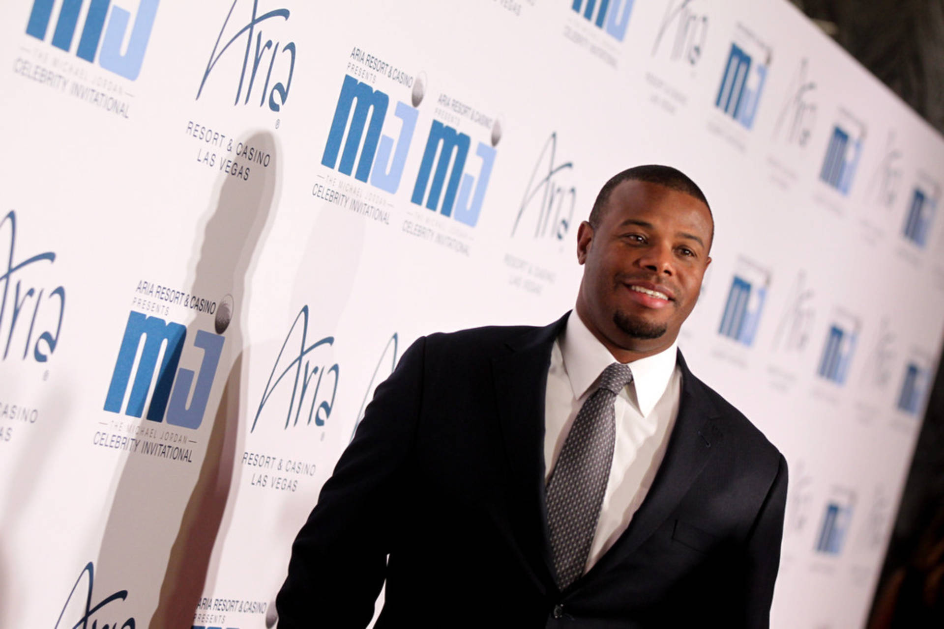 穿西裝的男子在品牌背景的活動紅地毯上微笑。 — Michael B Jordan 壁紙