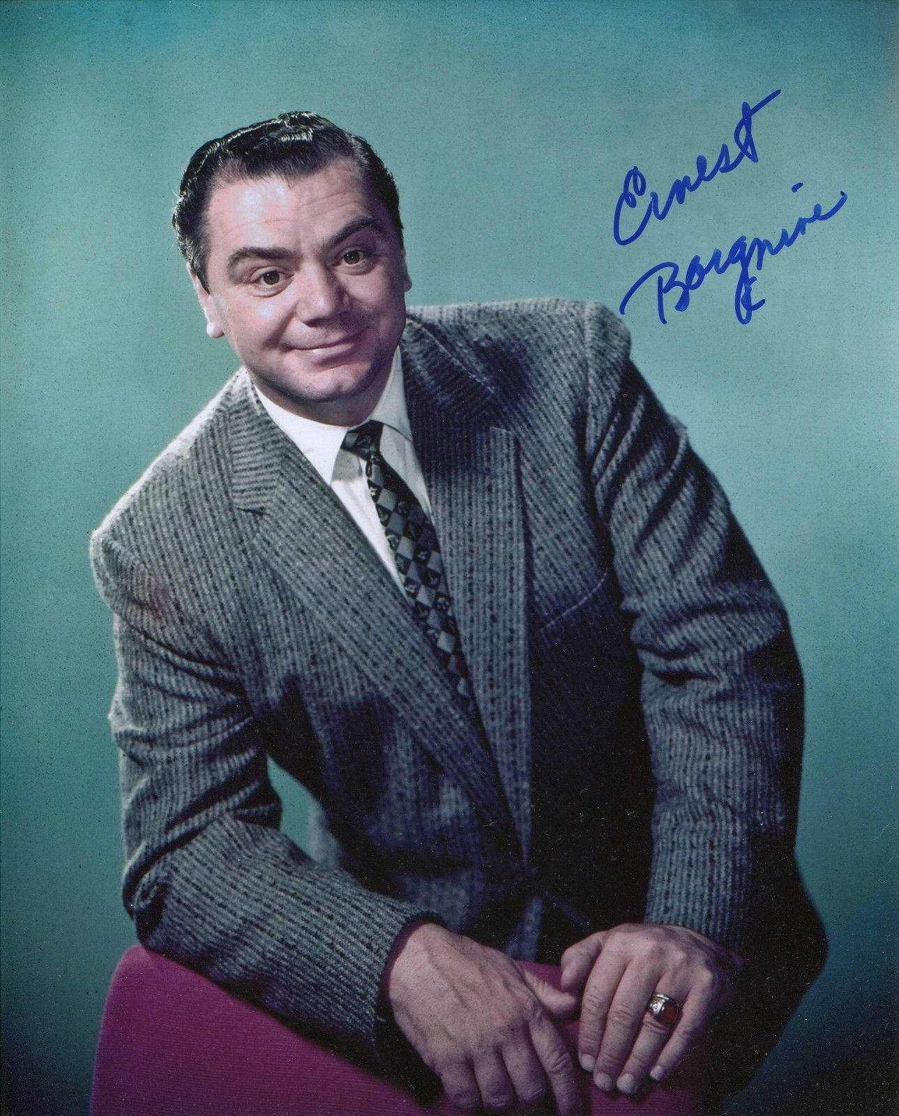 actor 桌布 壁紙 — 一位微笑的男子身穿細條紋西裝，在青綠色背景前擺姿勢，並附有藍色墨水的簽名。