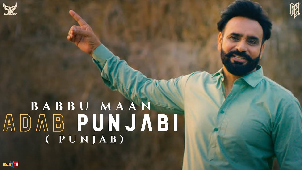Babbu Maan 桌布 壁紙 — 一位微笑的男子身穿青綠色襯衫，自信地指向模糊的岩石背景，並帶有粗體文字疊加。