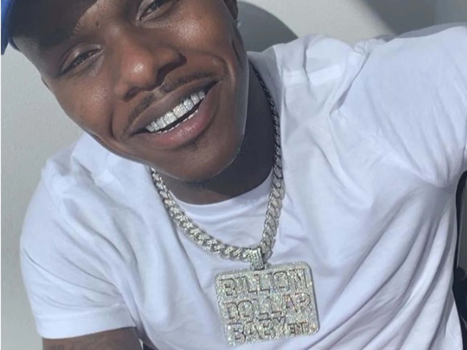 Dababy 桌布 壁紙 — 一位微笑的白T恤男士戴著一條鑲有鑽石的大鏈條，上面掛著一個'BILLION DOLLAR BABY'吊墜。
