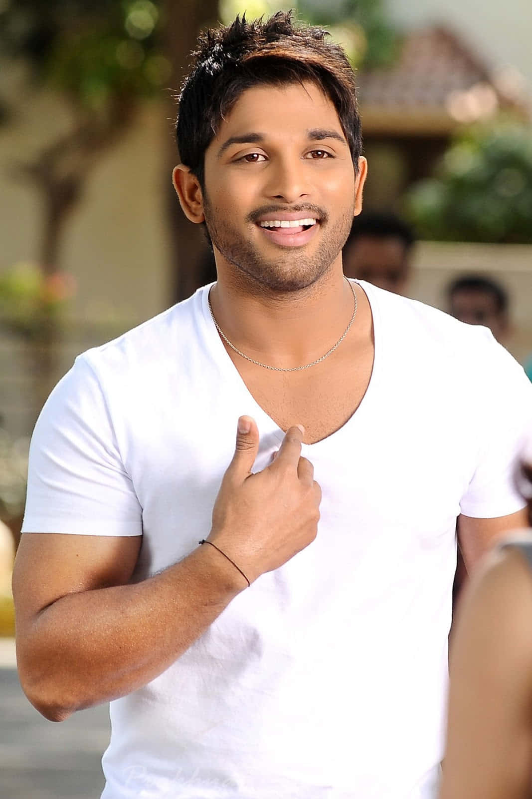 Allu Arjun 桌布 壁紙 — 一位微笑的白T恤男士指著自己的胸口，表情溫暖而自信。