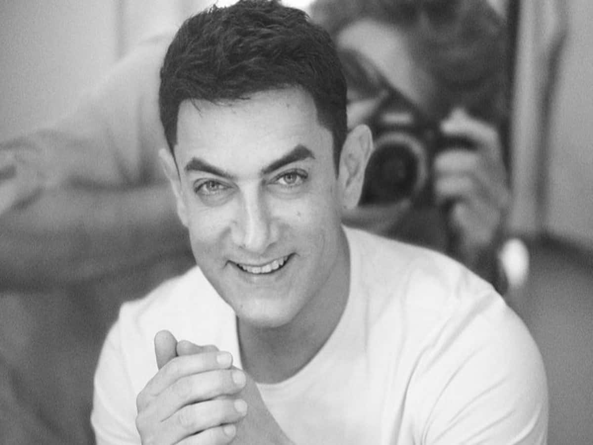 Aamir Khan 桌布 壁紙 — 一位微笑的白T恤男士看向相機，攝影師正在為他拍攝黑白肖像。