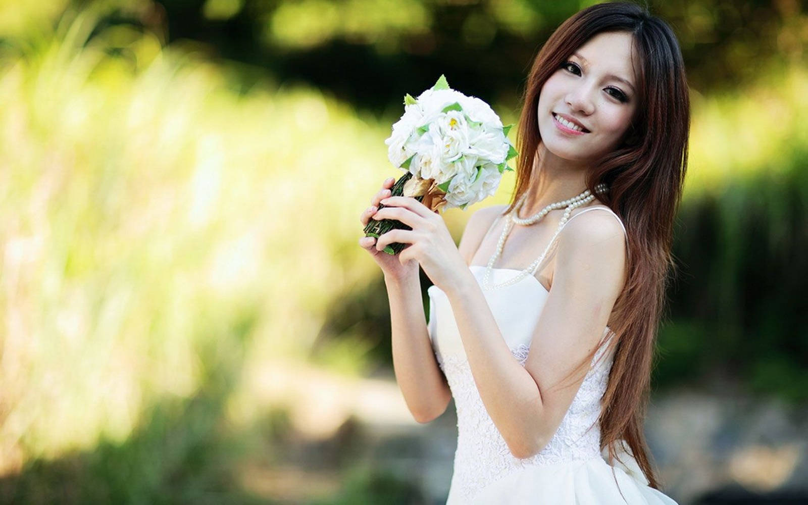 美女 桌布 壁紙 — 一位微笑的白裙女士在陽光普照的綠色背景下手持一束白色鮮花。