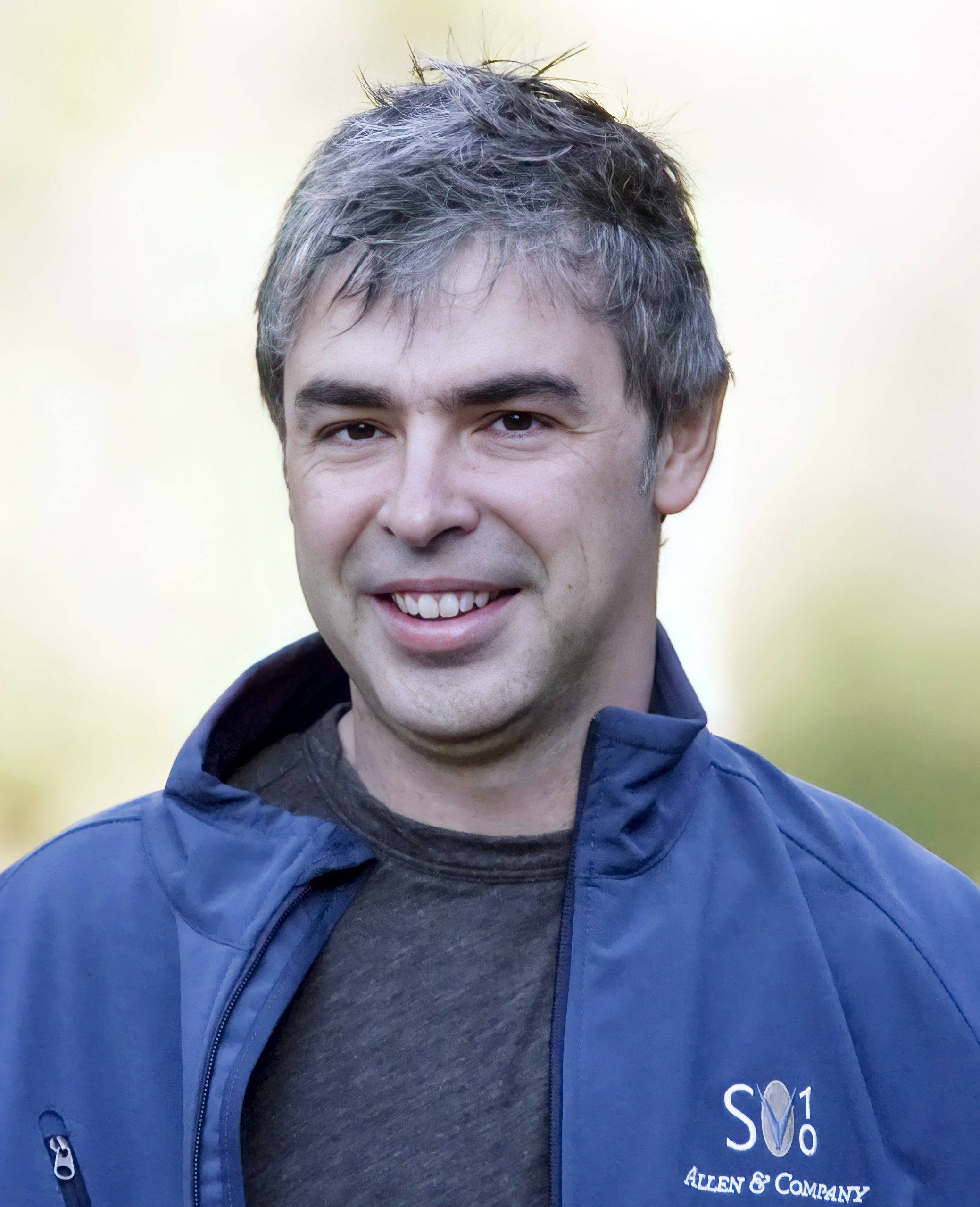google 桌布 壁紙 — 一位微笑的白髮男士穿著藍色 Allen & Company 外套，背景柔和模糊。