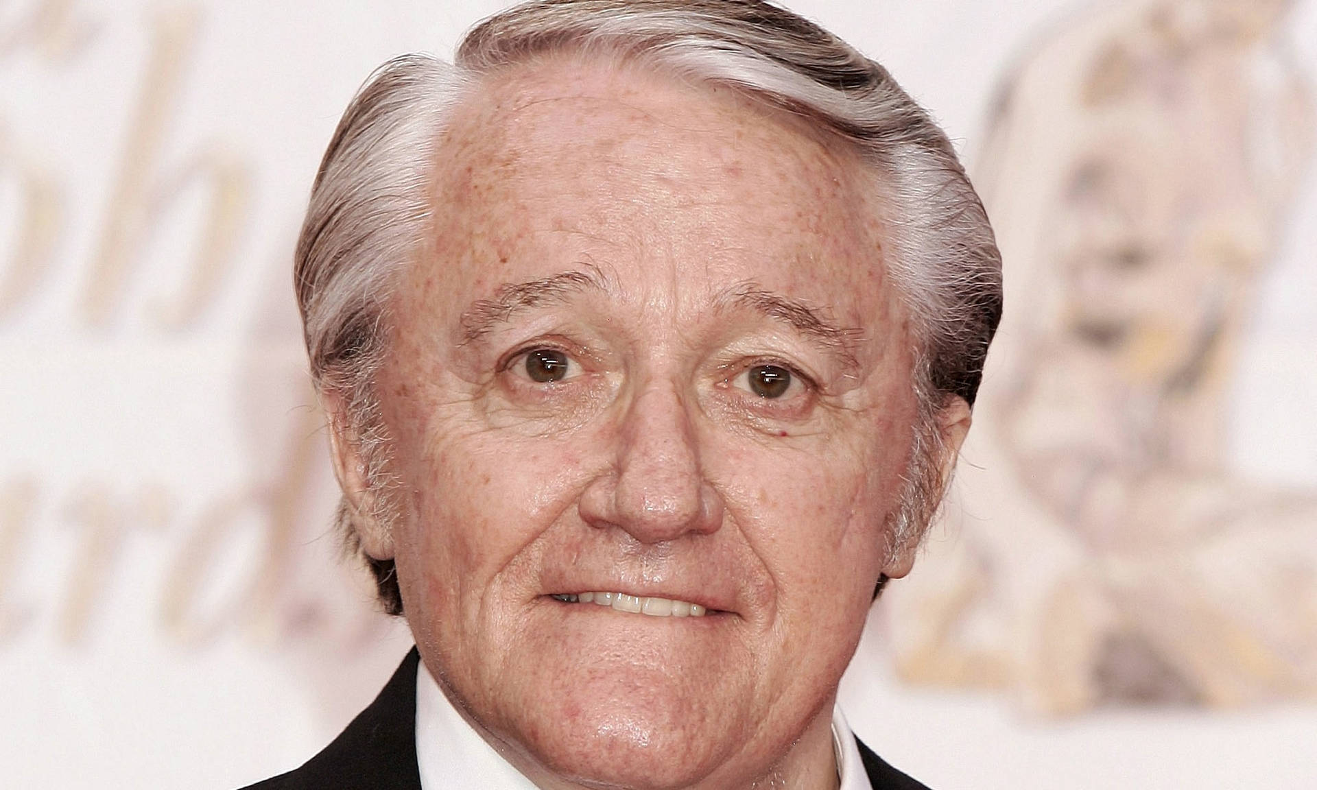 Celebrity 桌布 壁紙 — 一位微笑的白髮老年男士身穿黑色西裝和白色襯衫，在模糊的頒獎背景前的特寫肖像。