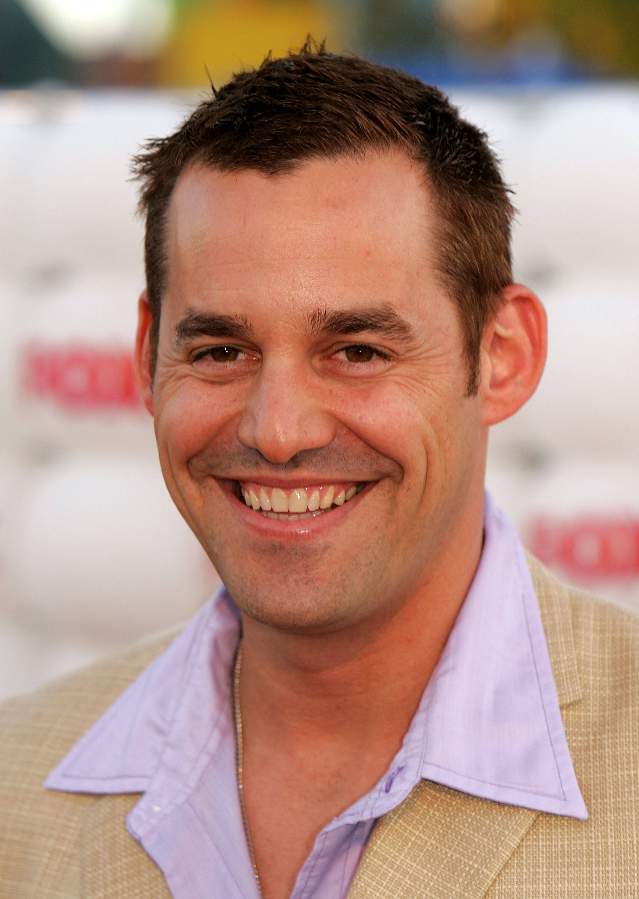 Nicholas Brendon 桌布 壁紙 — 一位微笑的短棕髮男士在紅毯活動中穿著米色外套，內搭淺紫色襯衫。