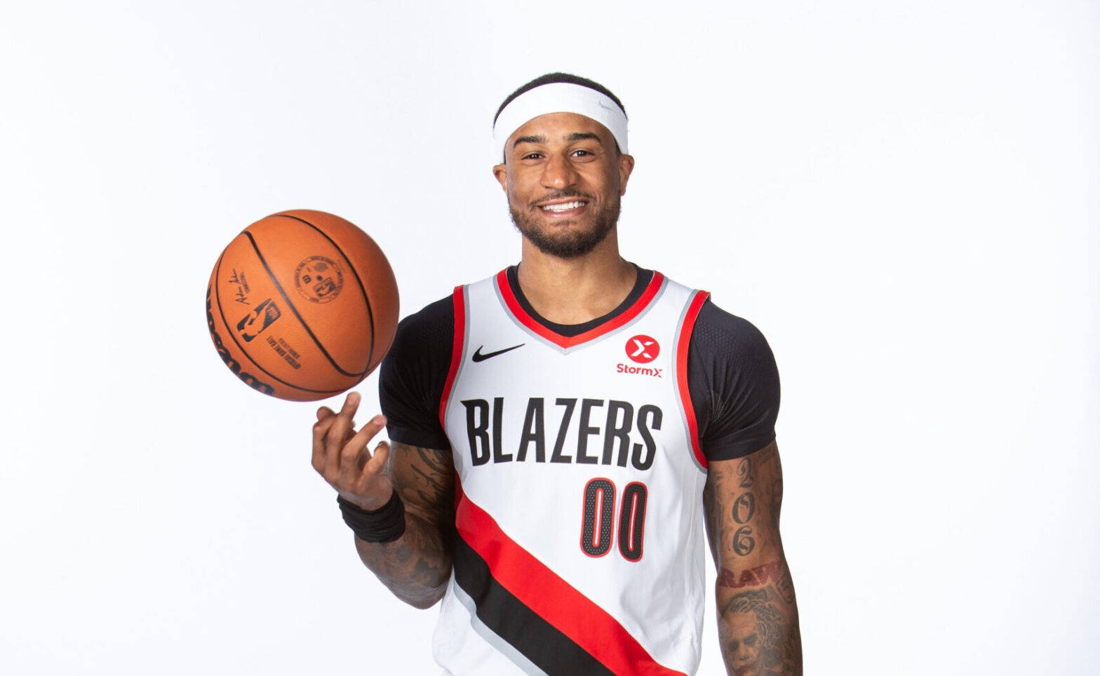 NBA 桌布 壁紙 — 一位微笑的籃球運動員穿著 Blazers 球衣，在純白背景下旋轉籃球。