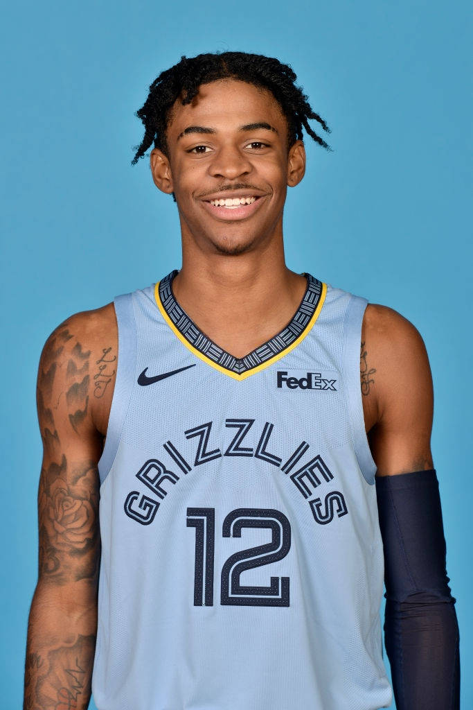 Ja Morant 動圖 桌布 壁紙 — 一位微笑的籃球運動員身穿淺藍色灰熊隊12號球衣，在純藍色攝影棚背景前擺姿勢。