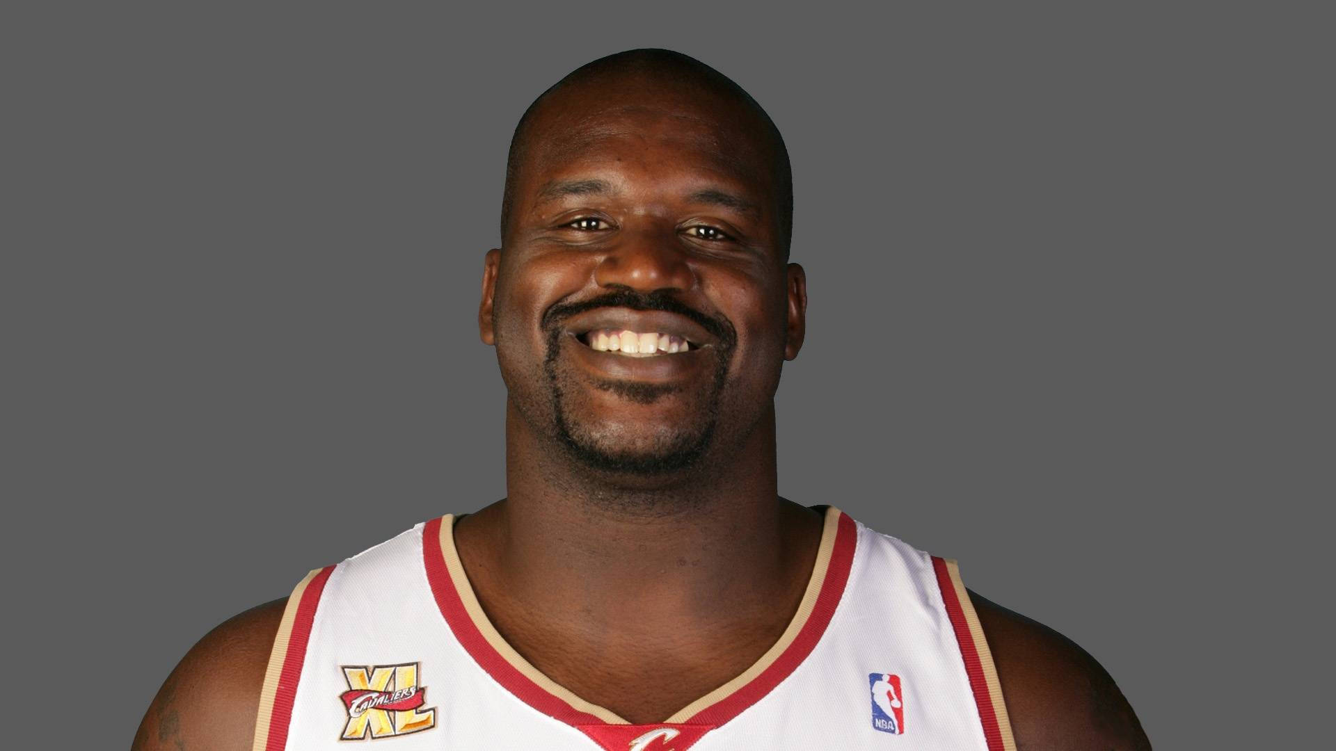 Shaquille O'neal 桌布 壁紙 — 一位微笑的籃球運動員身穿白色和紅色球衣，在純灰色工作室背景前擺姿勢。