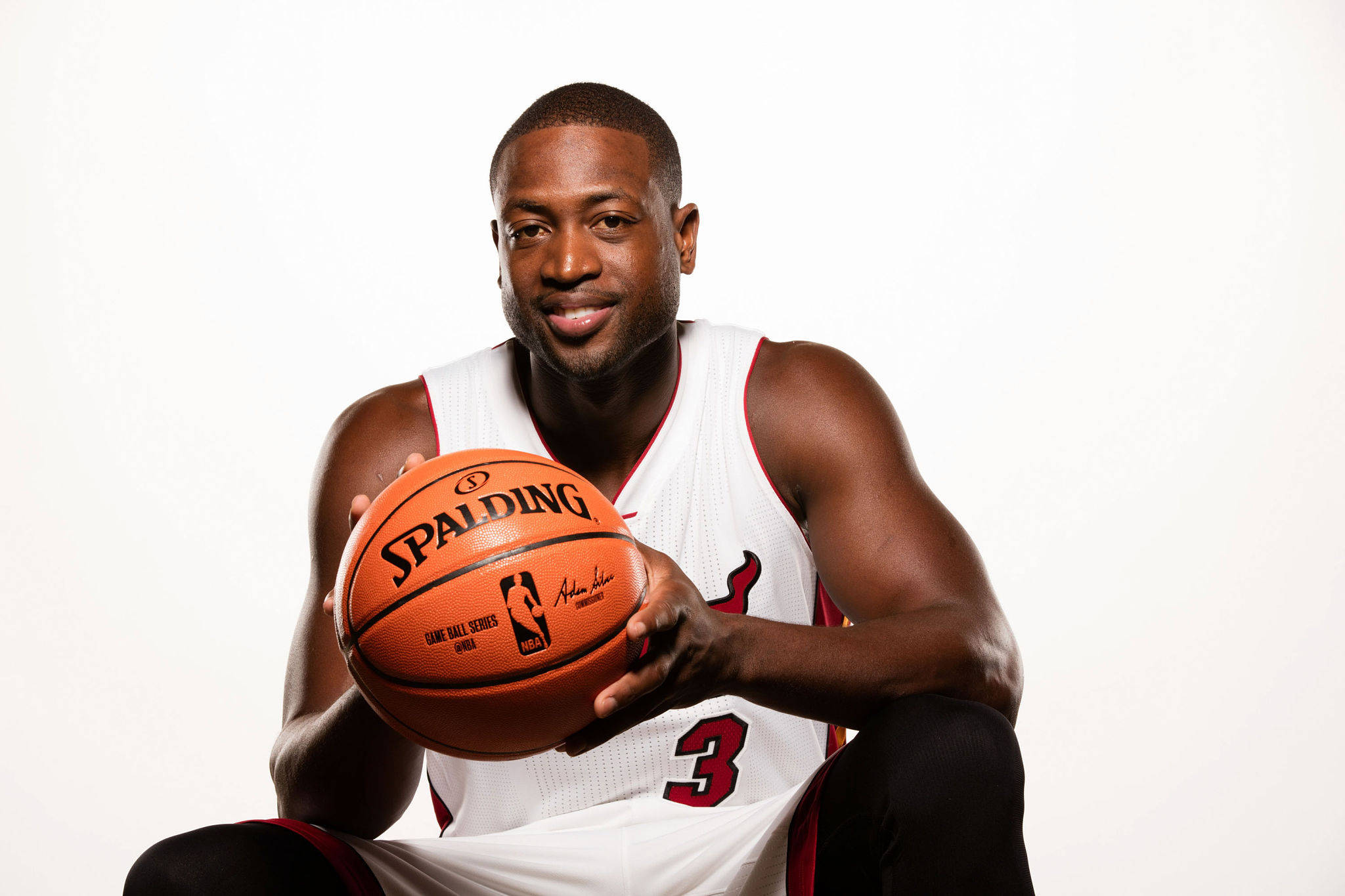 NBA 桌布 壁紙 — 一位微笑的籃球運動員身穿白色球衣，在純白色背景前拿著一個橙色的 Spalding 籃球。